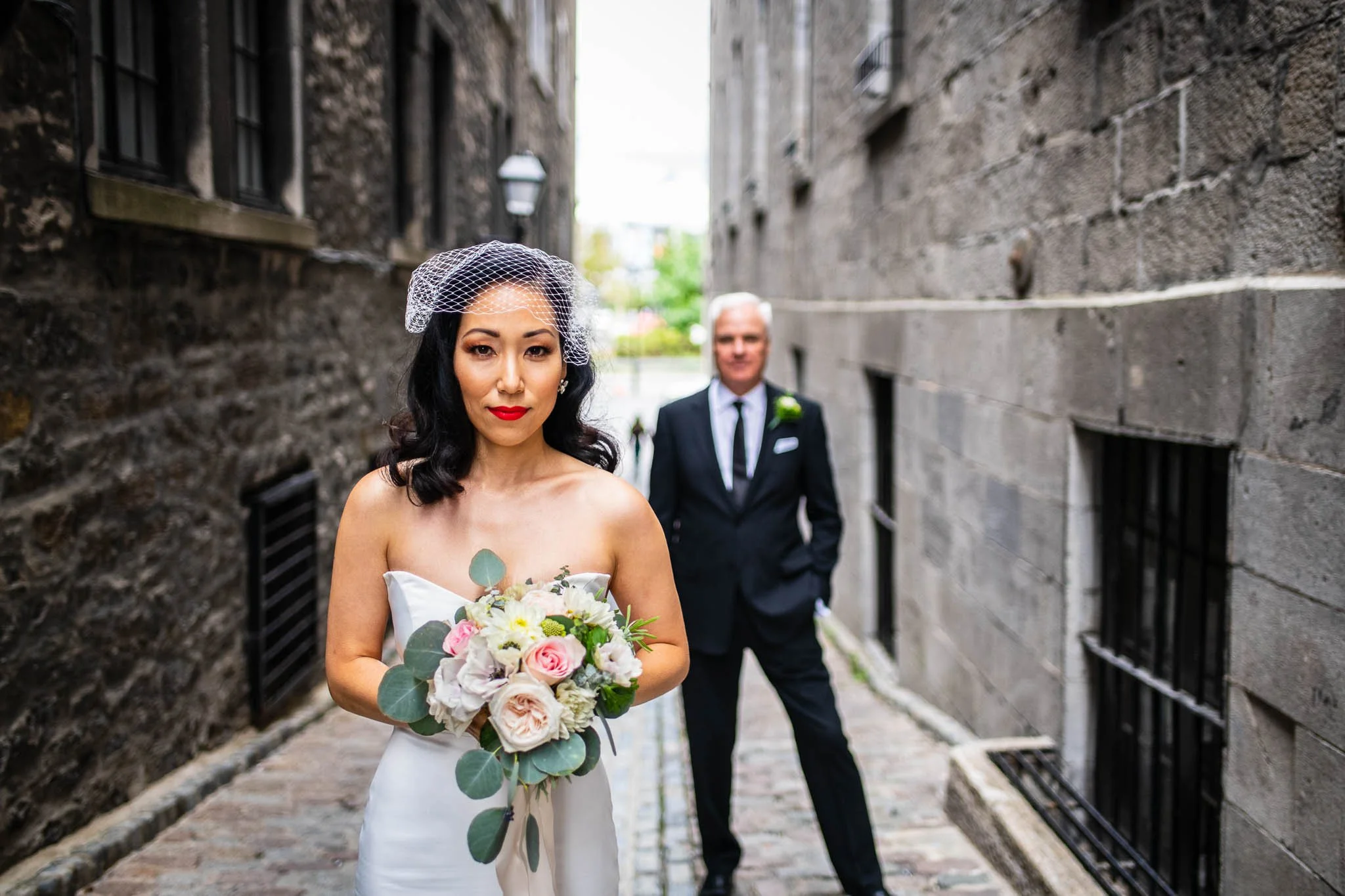 bride in foreground groom background standing seriously looking into camera