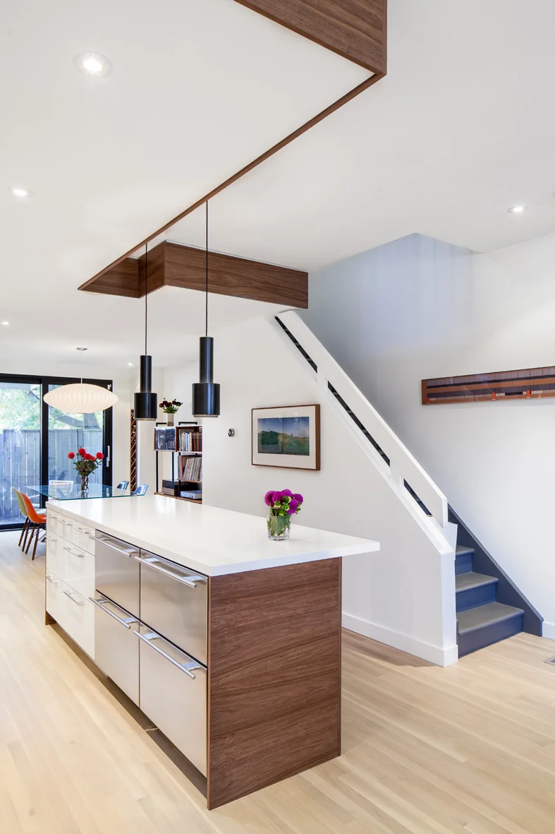 The wood wraps around the room, framing the light pendants, and ties together the spaces with a striking graphic quality