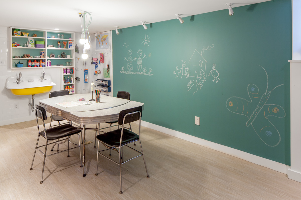 As a flexible and multifunctional space meant to adapt to the lives and needs of the children as they grow up, the basement includes workspace featuring a vintage trough sink for arts and crafts and science experiments. The chalkboard wall allows for impromptu doodling, planning hockey plays and sketching out ideas.