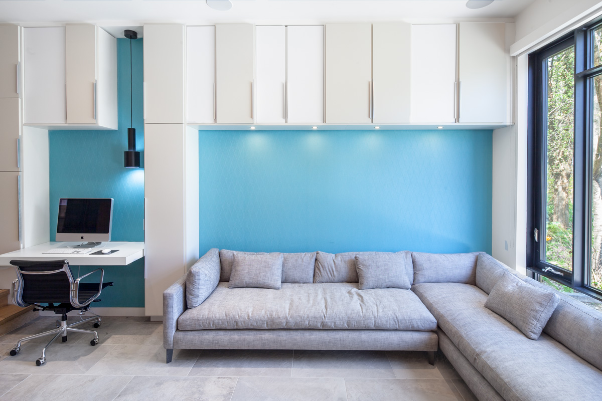 Recessed niches within the storage wall are accented by a turquoise wall-covering and accommodate a desk and generous couch in the living room. The radiant-heated floor makes the tile floor a durable choice that is comfortable year-round.