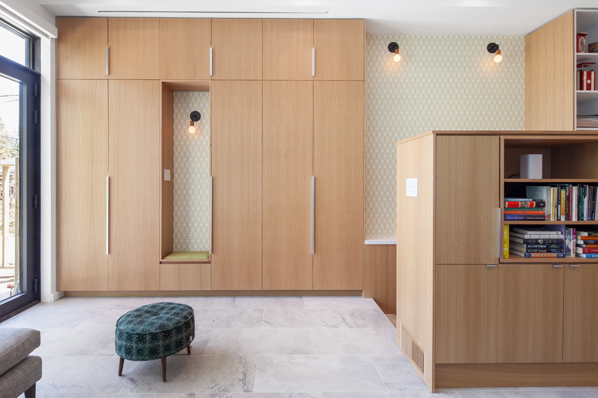 Floor-to-ceiling closets store shoes and jackets for children coming inside from the back yard. A niche is carved into the cabinetry to form a small bench for comfort taking shoes on and off.