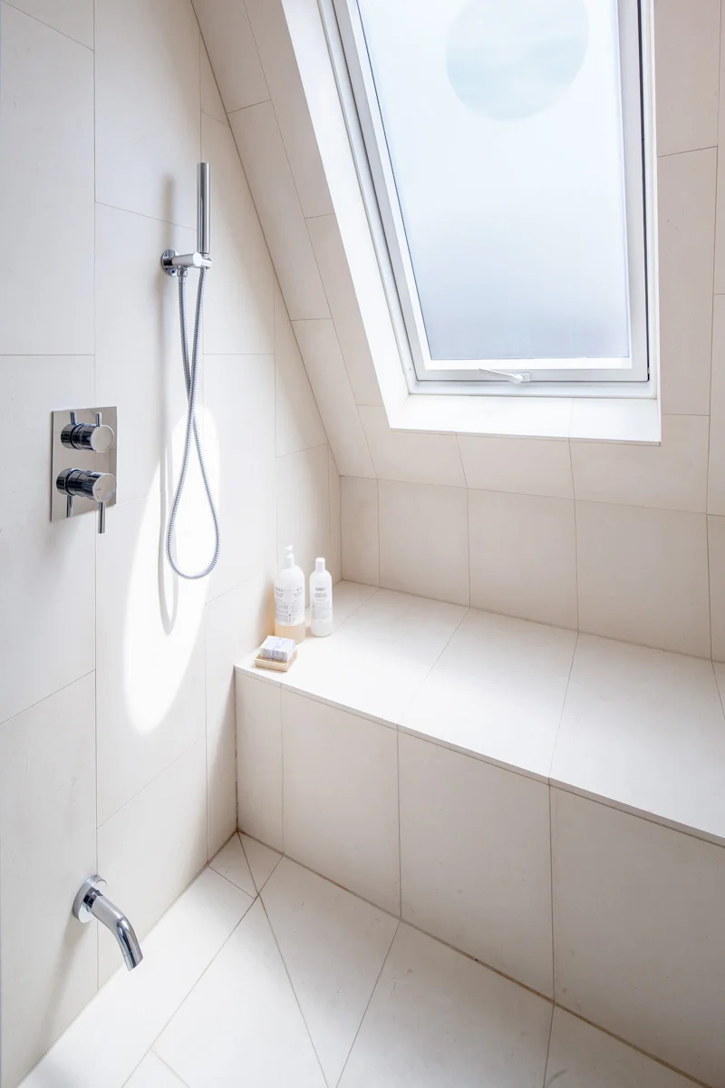 The frosted glass skylight and built-in bench gives the spacious master ensuite shower a modern, spa-like feel.