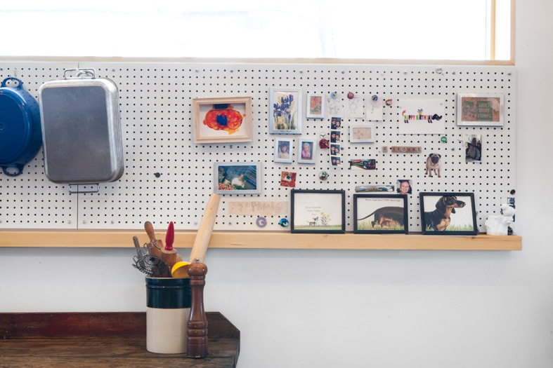 A wood shelf links the kitchen and dining rooms together - in places it becomes a deep sill by the kitchen window for plants and herbs, here in the dining room it becomes a ledge for family photos and kids’ art.