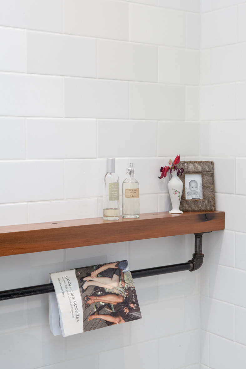 A simple rod fashioned from standard plumbing components hangs from the custom redwood shelf.