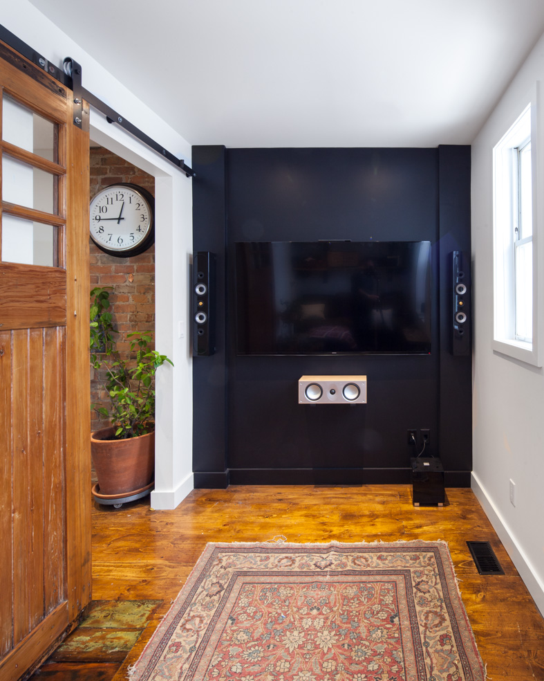 The upstairs family room becomes a cozy spot for movies and relaxing. A reclaimed wood door slides on a custom track.