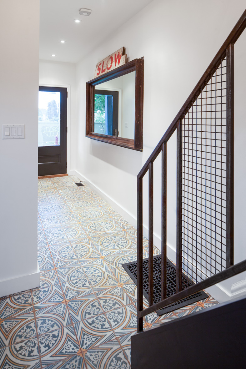 The entry foyer features the texture, colour and character of the encaustic tile floor set against clean white walls accented by old components of the original home.