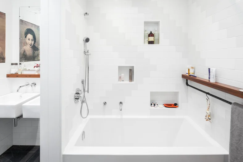 Inset niches in the shower provide space for storing bath products at the heights of various family members.