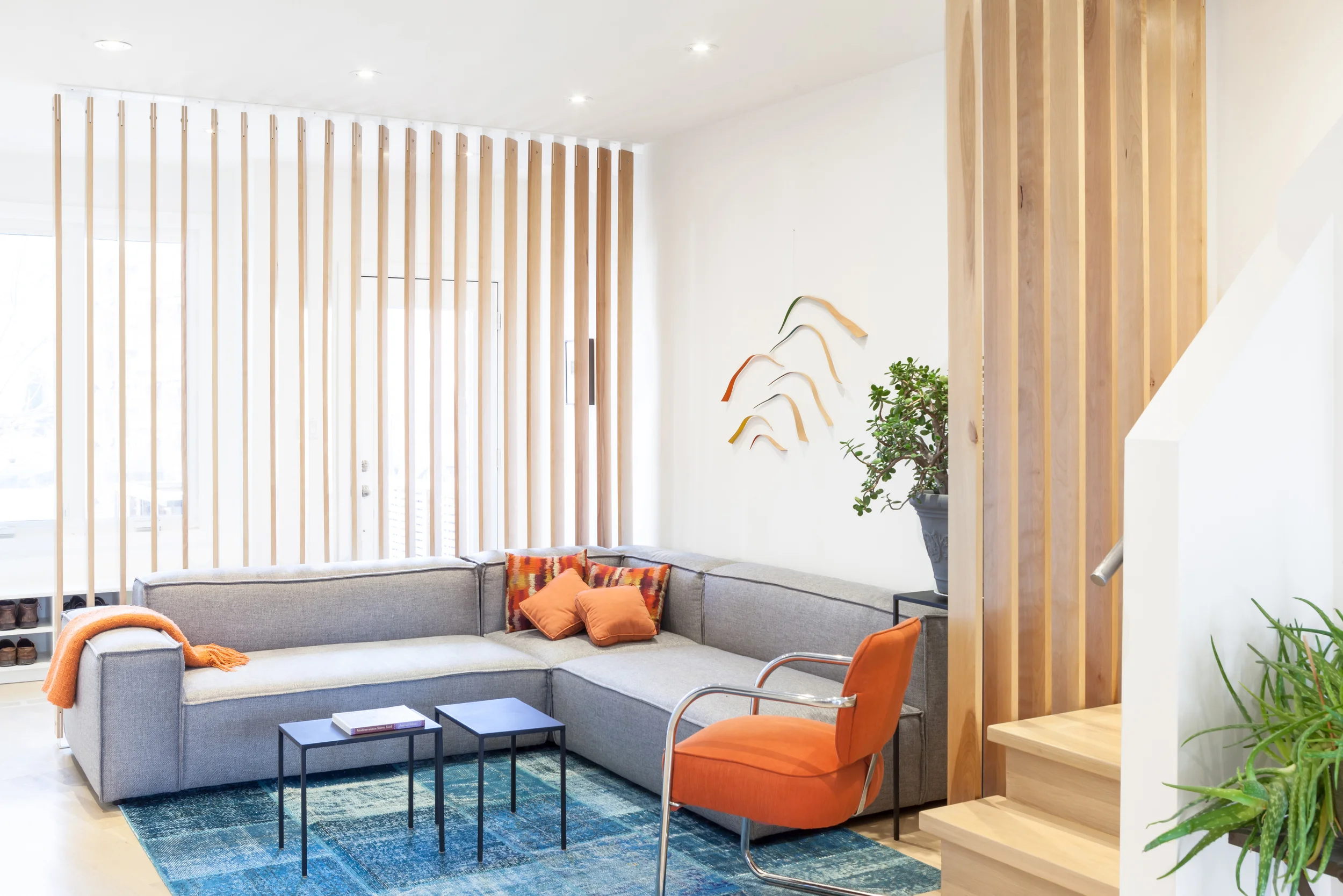 Despite being close to the front door, the living room feels comfortably enclosed by wood slats that are angled to provide privacy from the street while sitting on the generous sectional sofa, but still permit light to shine into the rest of the house.