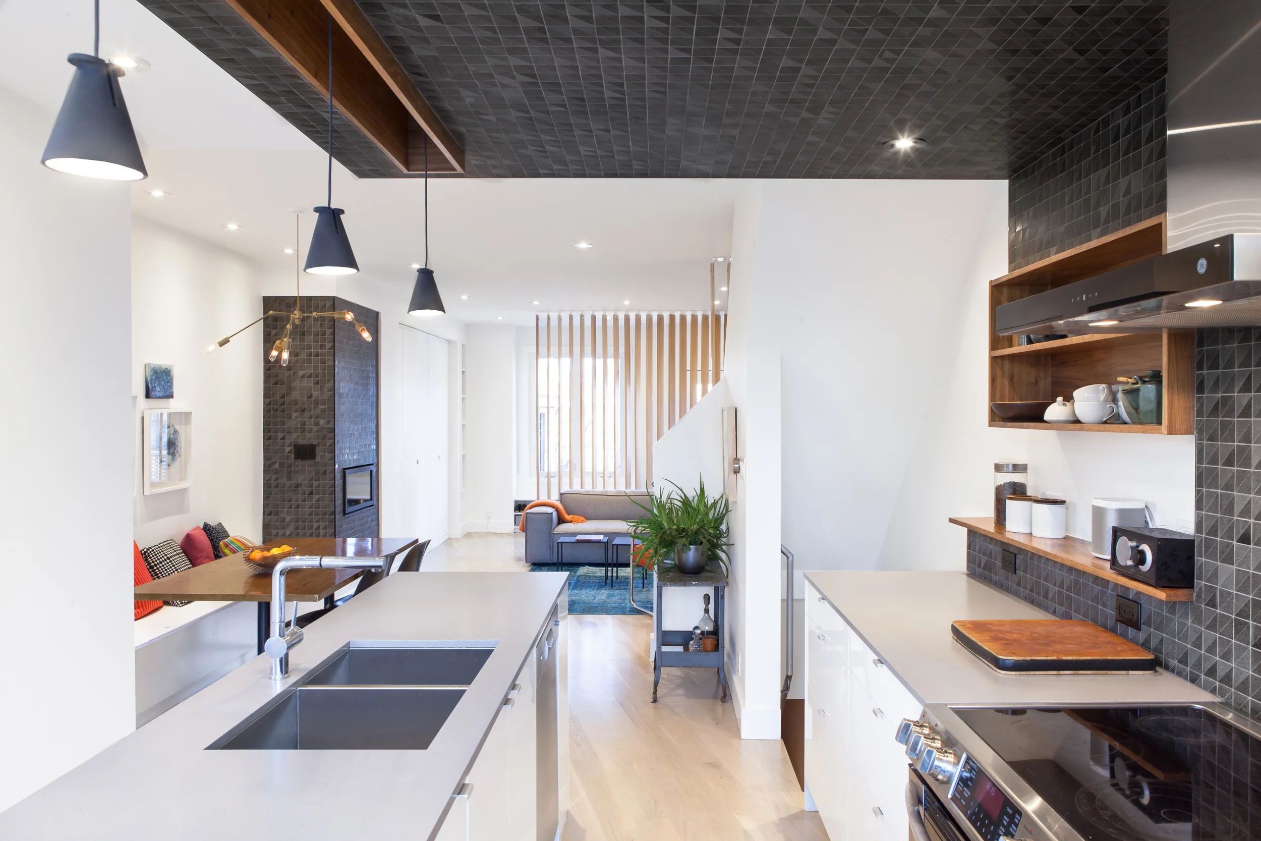 The black tile is a bold graphic gesture that defines the kitchen space within an open-concept floor plan, and relates to the fireplace in the living room - visually, and conceptually, these are two ‘heaths’ that anchor the home and attract the fam