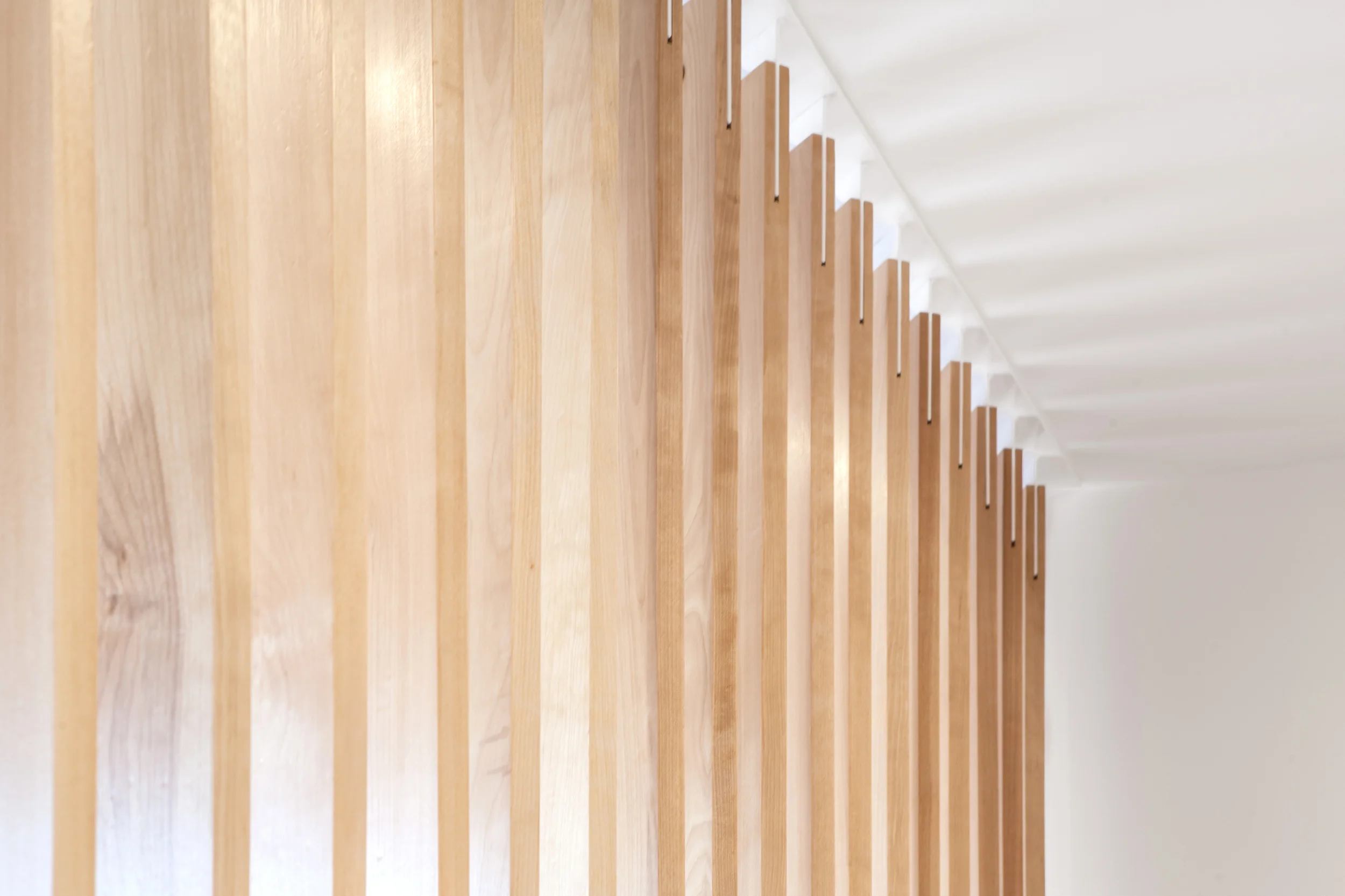 Solid birch slats are meticulously fastened to white painted steel fins at the floor and ceiling, and create an interesting play of light and shadows, particularly in the early morning light.