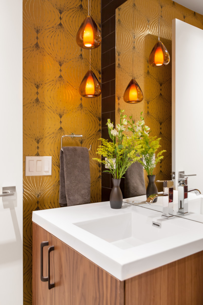 The warm glow of pendants dangling to the side of the powder room mirror provide an alluring warm glow.