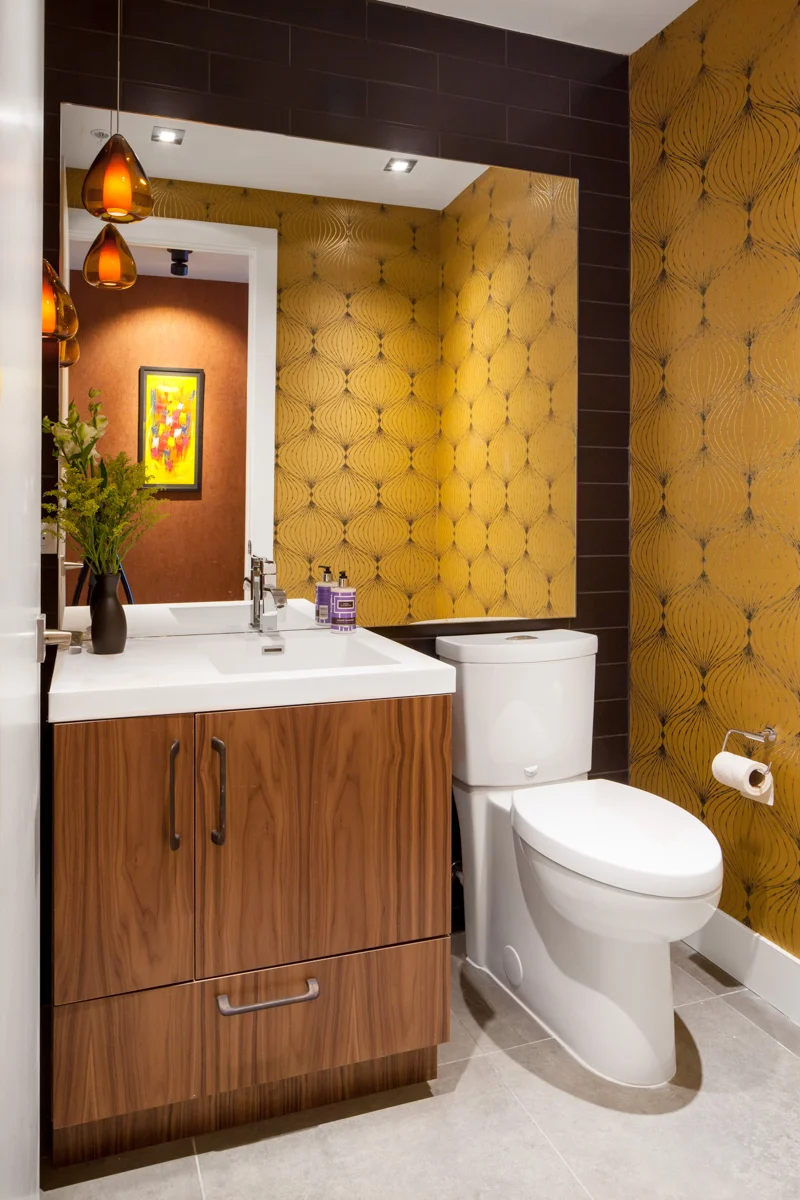 The powder room features a vibrant pop of saturated colour that complements a dark tile on one wall.