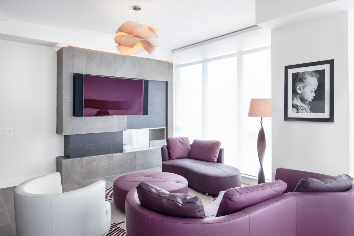 The living room is oriented towards a custom fireplace and TV wall and utilizes a unique furniture layout that can easily accommodate family movie nights, evenings entertaining guests by the fire, or a peaceful afternoon reading a book by the window with a view over the city.