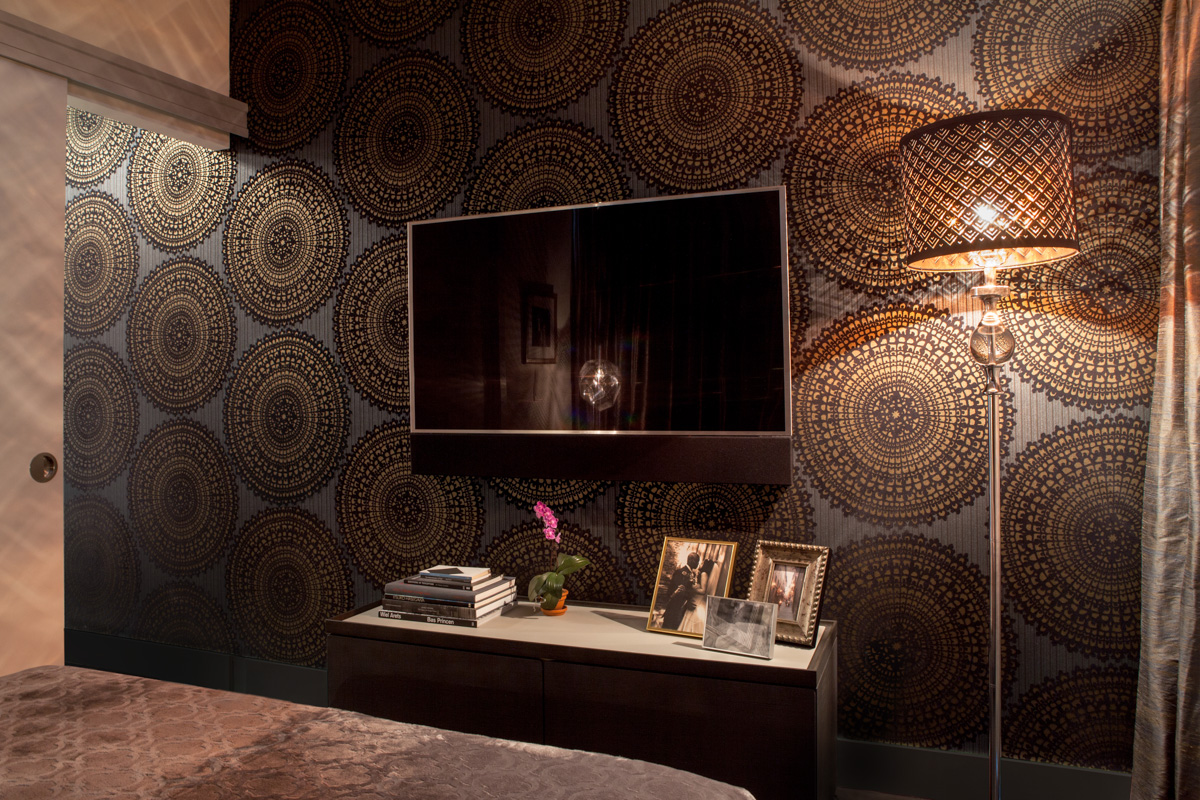 The bed is oriented towards a wall featuring a wall-covering of oversized gold medallions that extends beyond, down the corridor.