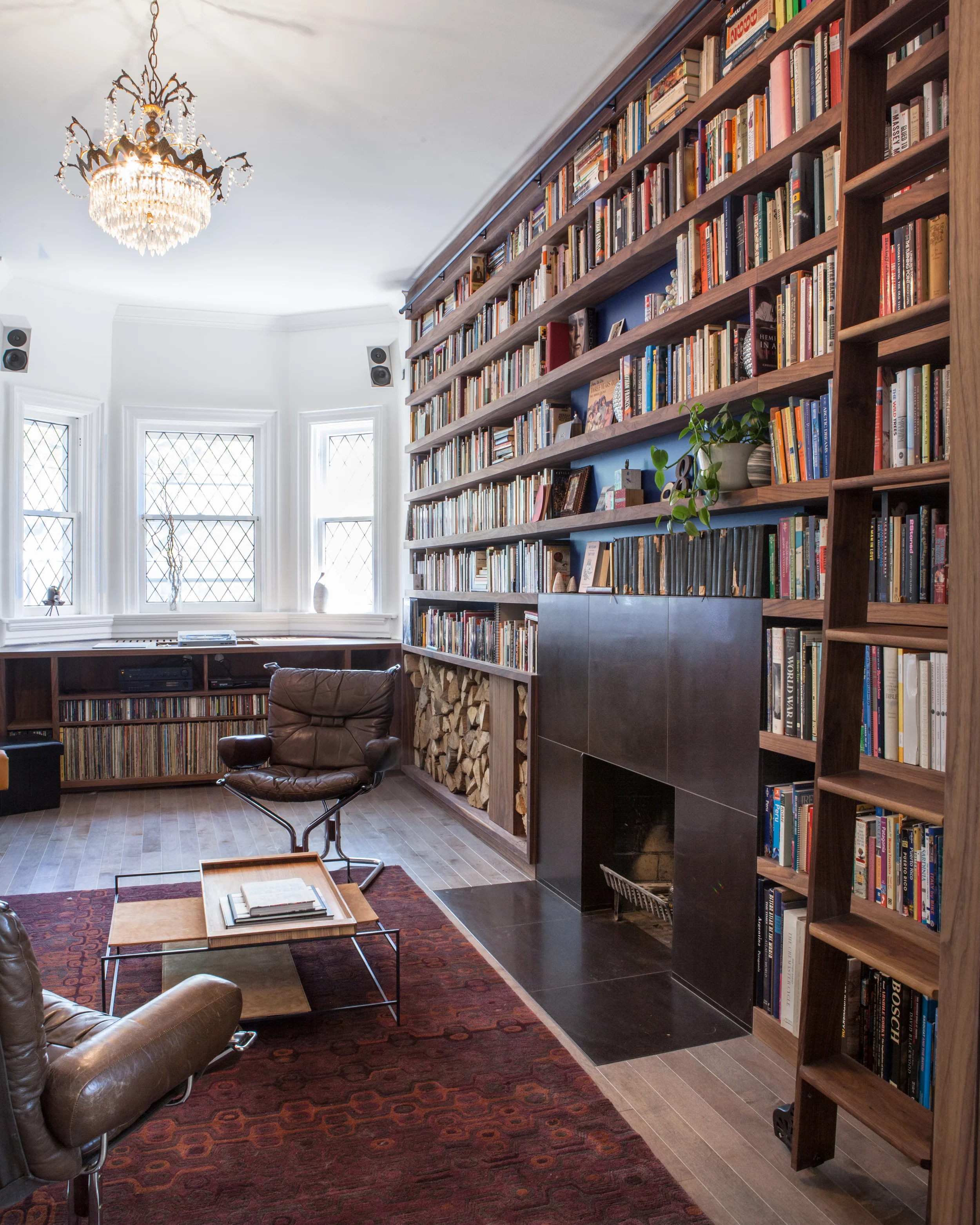 Bookshelves stretch from wall-to-wall, and floor-to-ceiling. Since the library is a working collection for the client, a bioethics scholar, a ladder rolls along the full length, to enable access to the uppermost shelves.