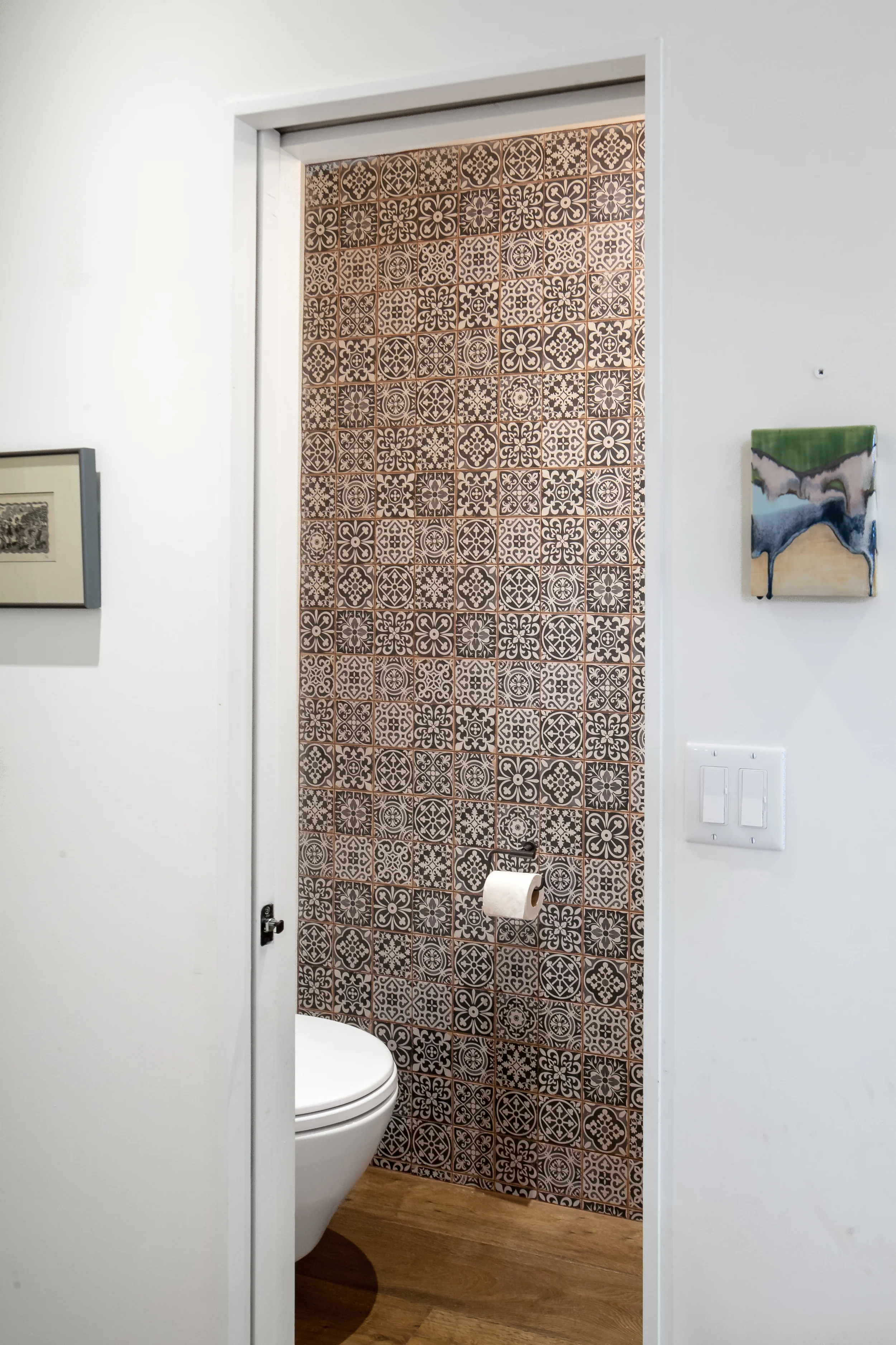 The powder room is tucked neatly off the corridor and features a mosaic of traditional black and white tile from floor to ceiling. 