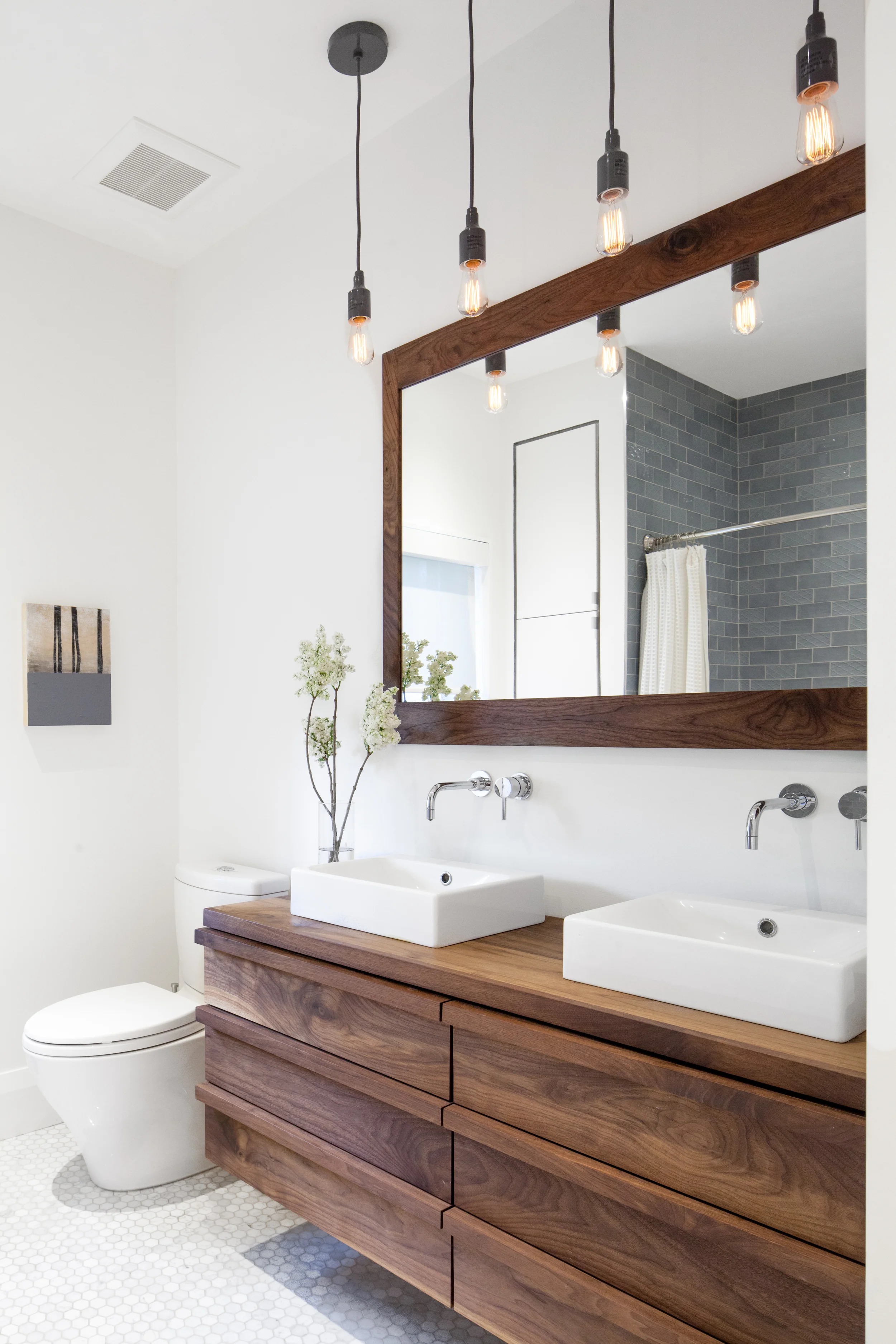 The ensuite features a custom vanity and mirror in solid walnut. Custom pulls are thoughtfully considered as part of the design, integrated into the drawer fronts. 