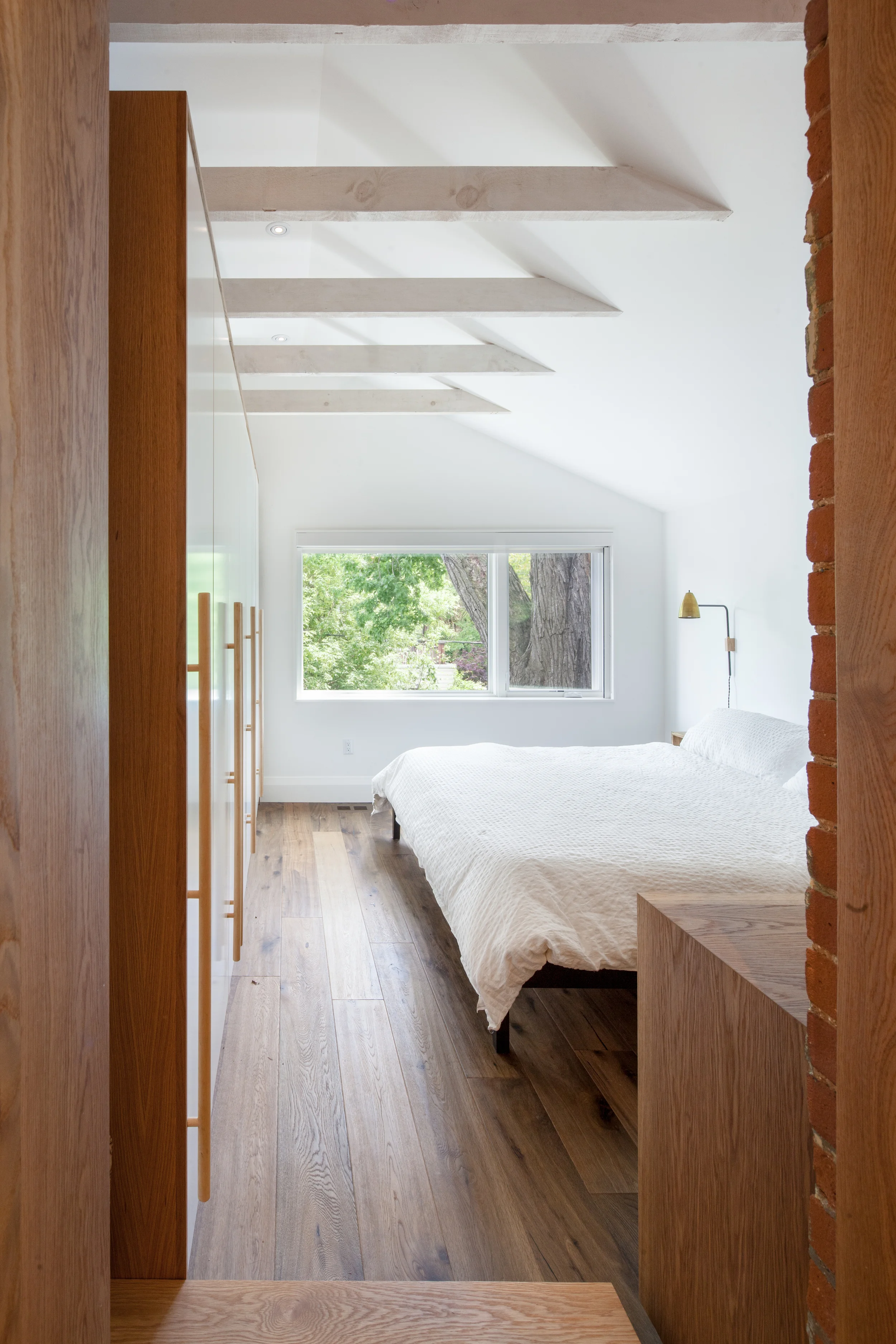 The master bedroom is a lofty space overlooking the rear yard, accessed through an existing brick opening.