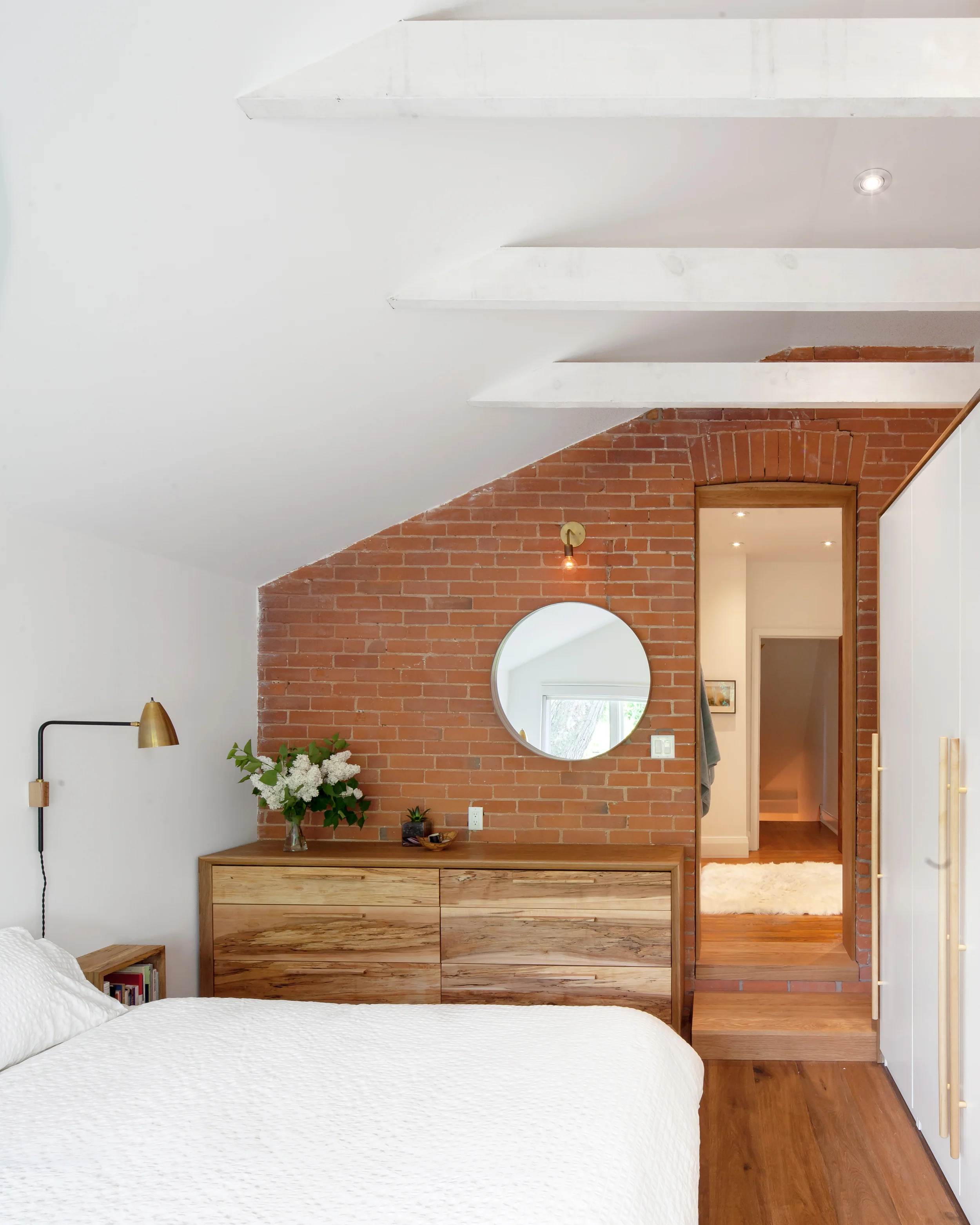 Exposed beams painted white, and the refinished original brick create a distinctive palette that is thoroughly modern, while still richly textured and respecting the home's historic bones.