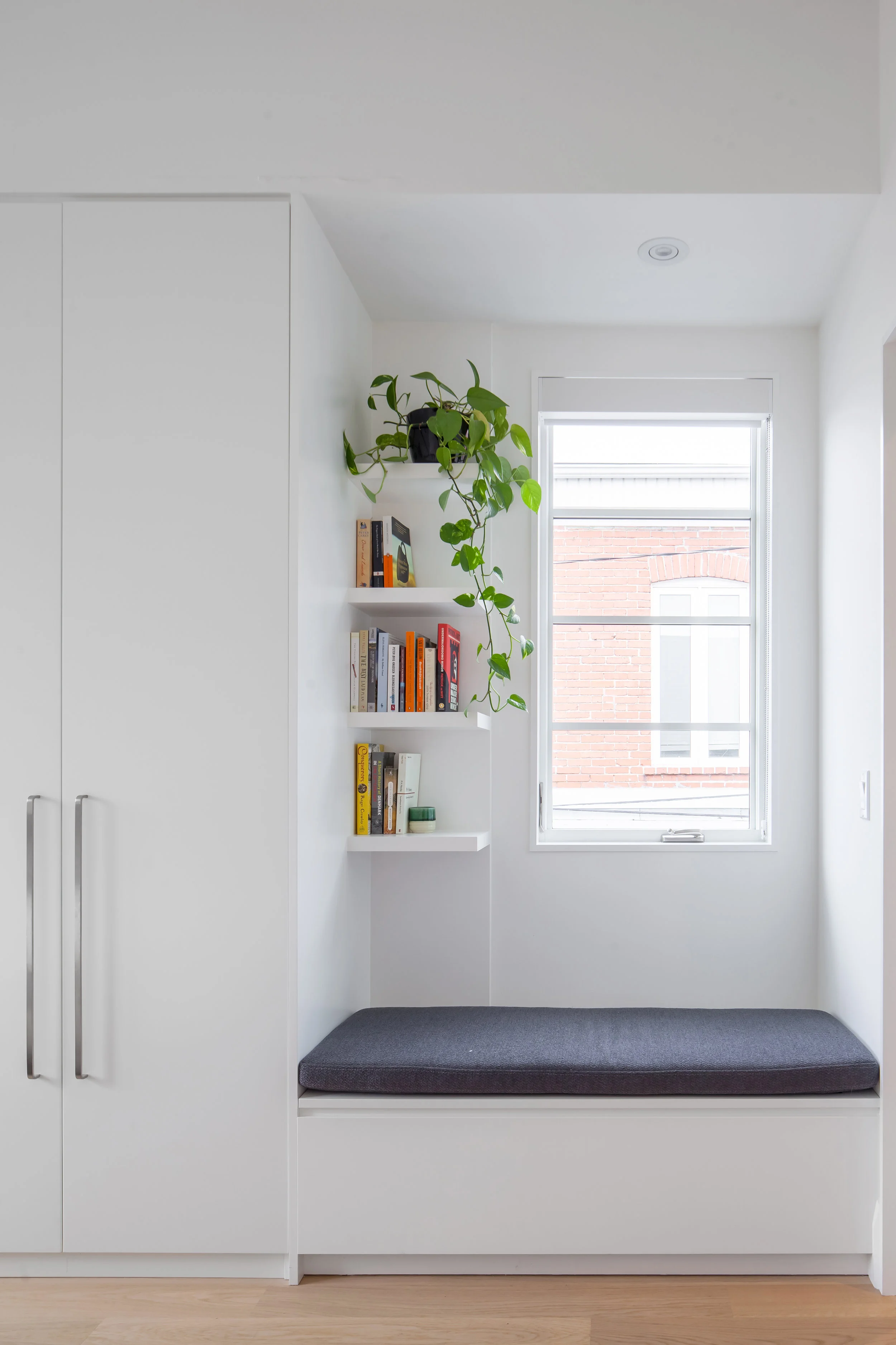 A window seat framed by closets and opens shelves is a cozy spot to sit and read.
