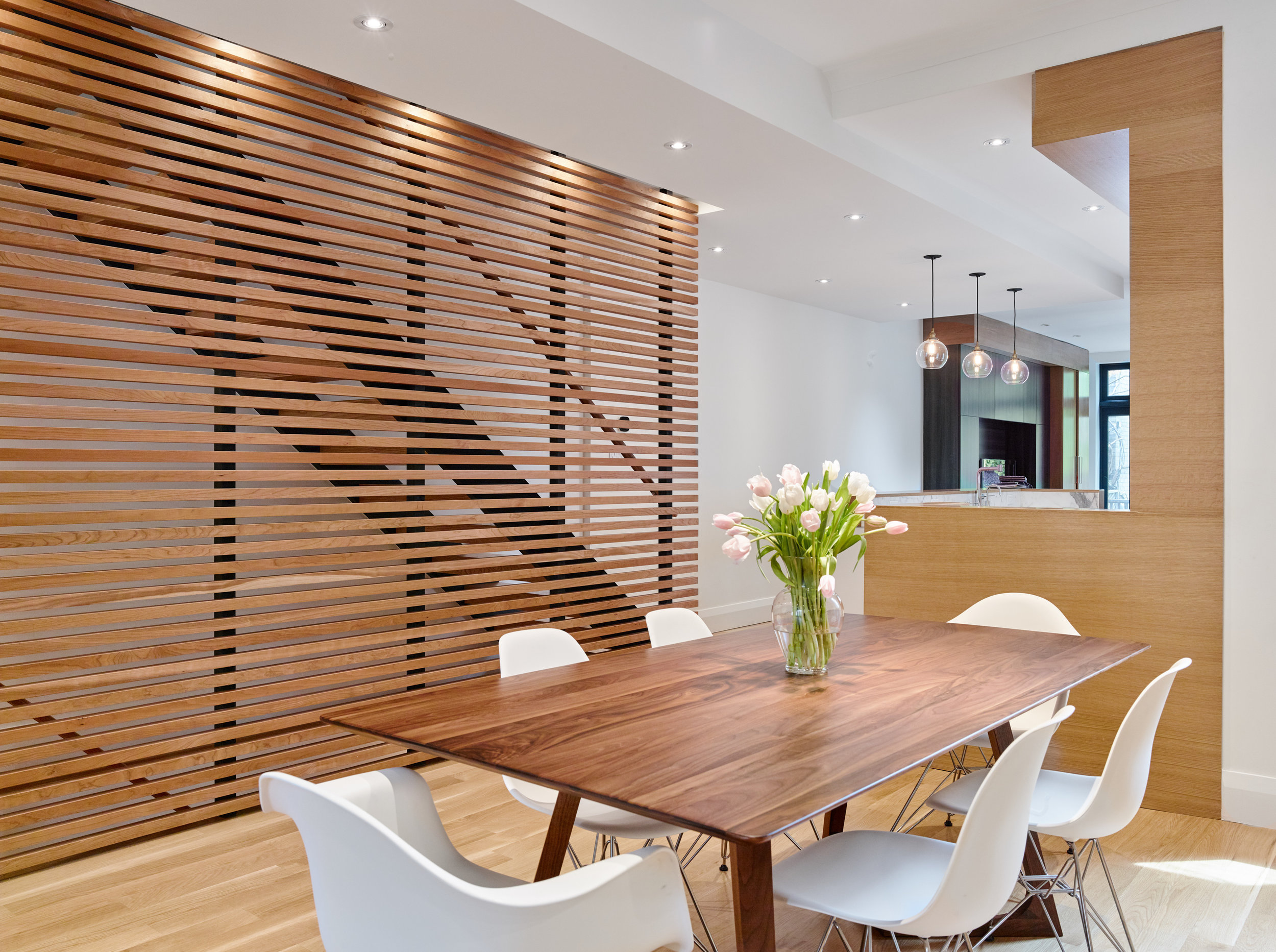 The wood slat feature wall acts as a grounding element in the middle of the open floor plan.