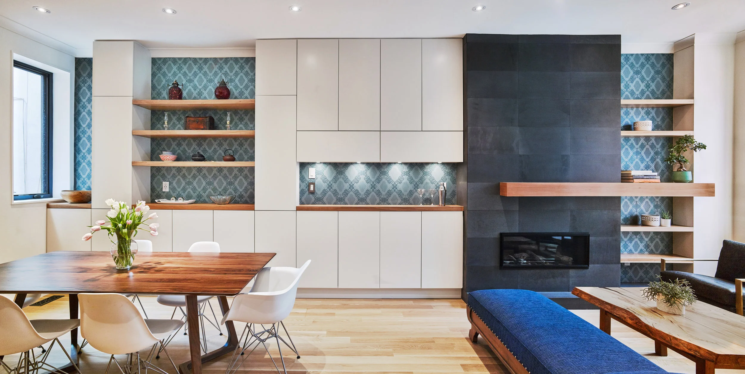 The custom millwork was influenced by the clients and their love of entertaining, and by including the fireplace, a bar and storage all on the same wall, it offers a seamless space with multiple functions. 