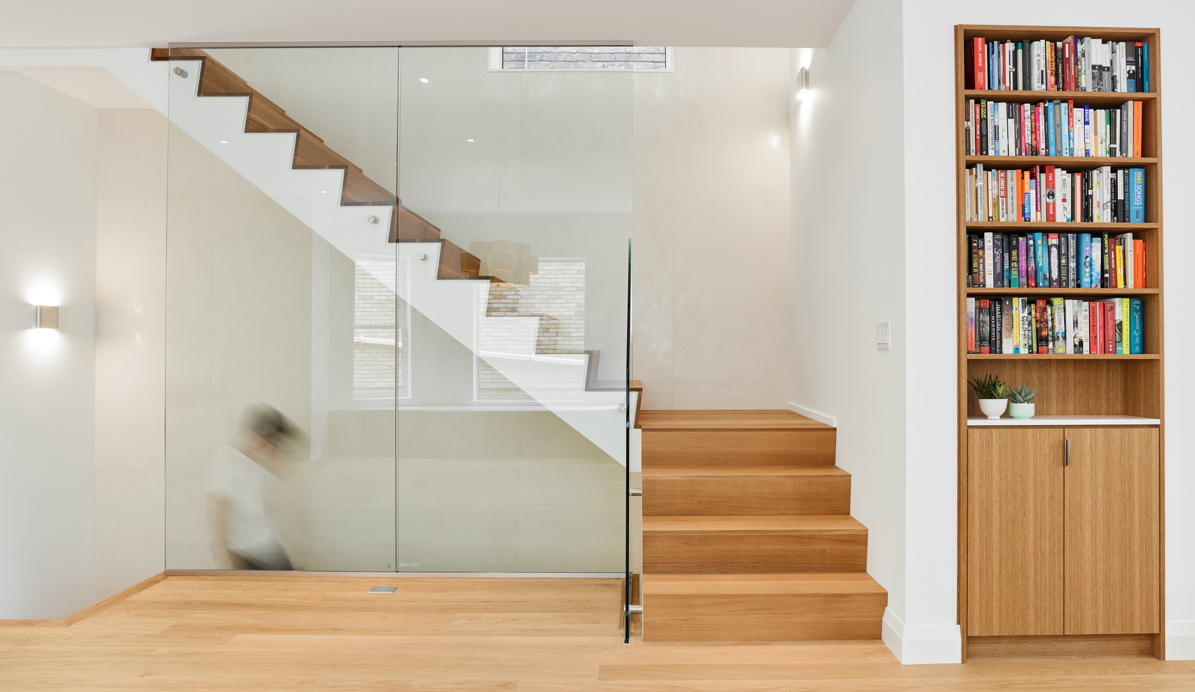 Angled white oak treads flow up the stairs to the second floor, against a three-storey tall wall of thin porcelain tile; a subtle move that ties the house together from top to bottom.
