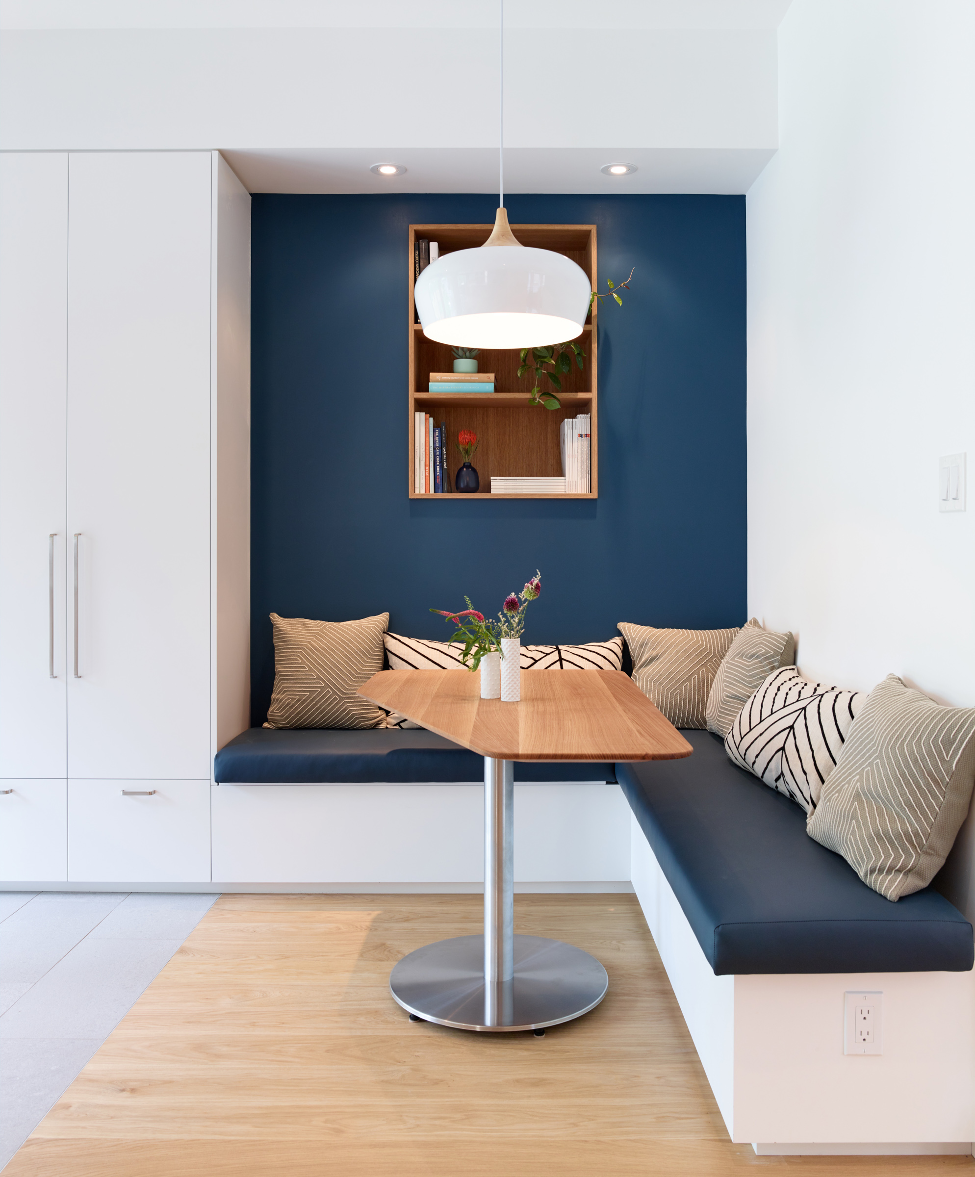The breakfast nook features a custom white oak table angled to maximize useable table space without impeding on the path of traffic to the backyard. The benches, upholstered in durable vinyl fabric, flip open to provide additional storage space.