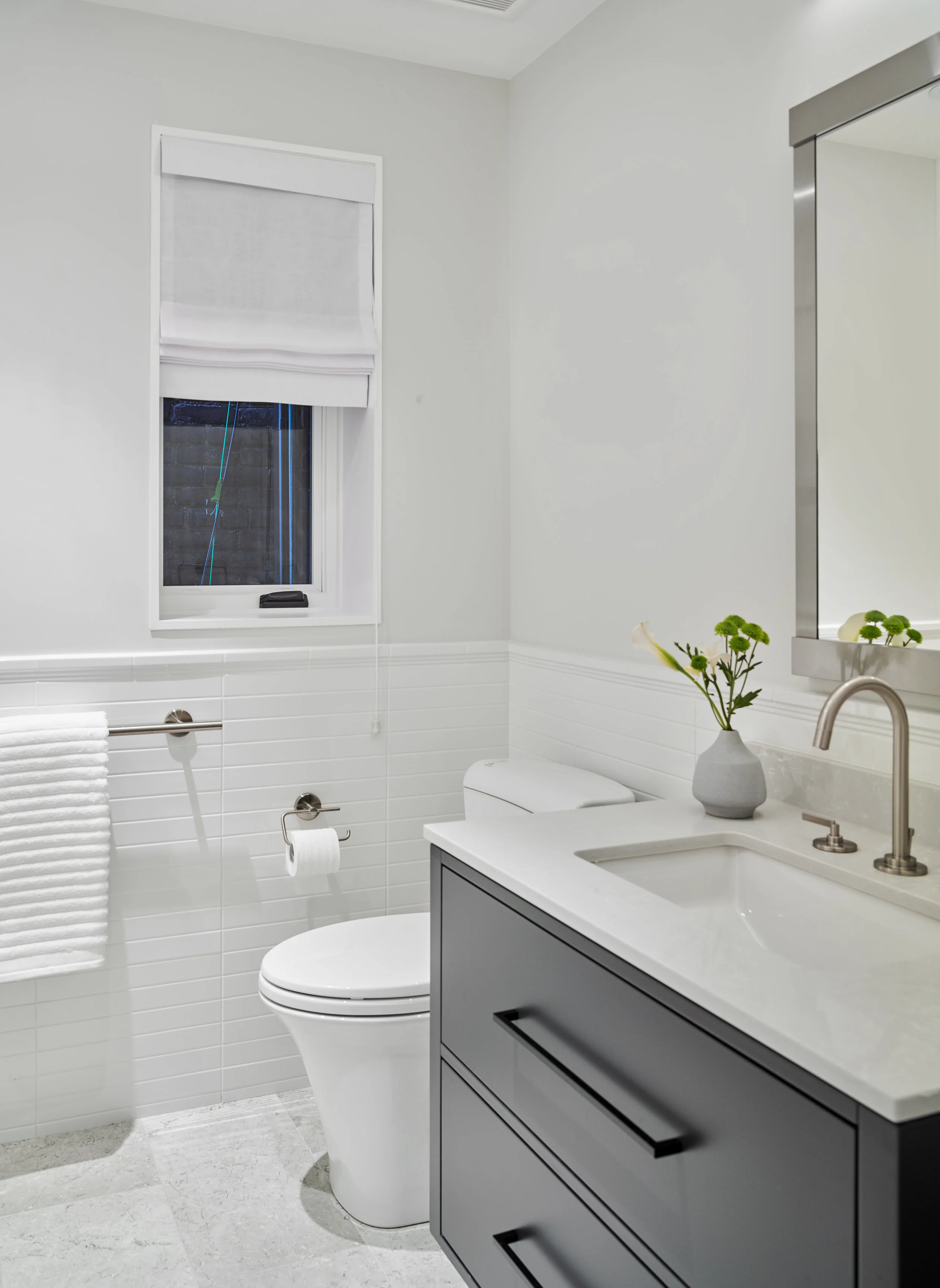 The shared bathroom stayed with the clean, crisp look, by offsetting the dark floating vanity with the white subway tile.