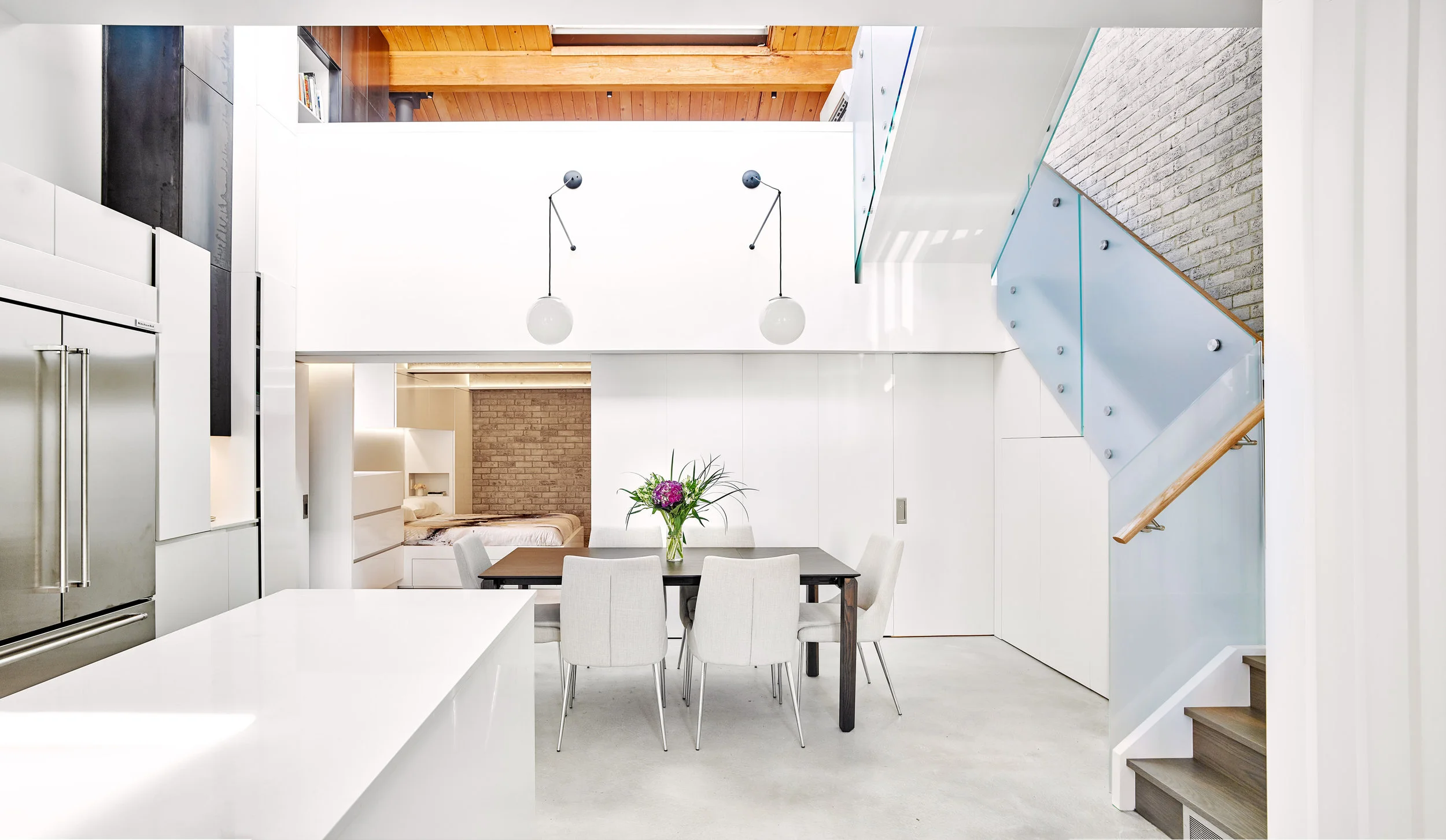 The kitchen and dining room occupy bright lofty spaces while the bedroom is tucked under the warmly lit mezzanine floor.