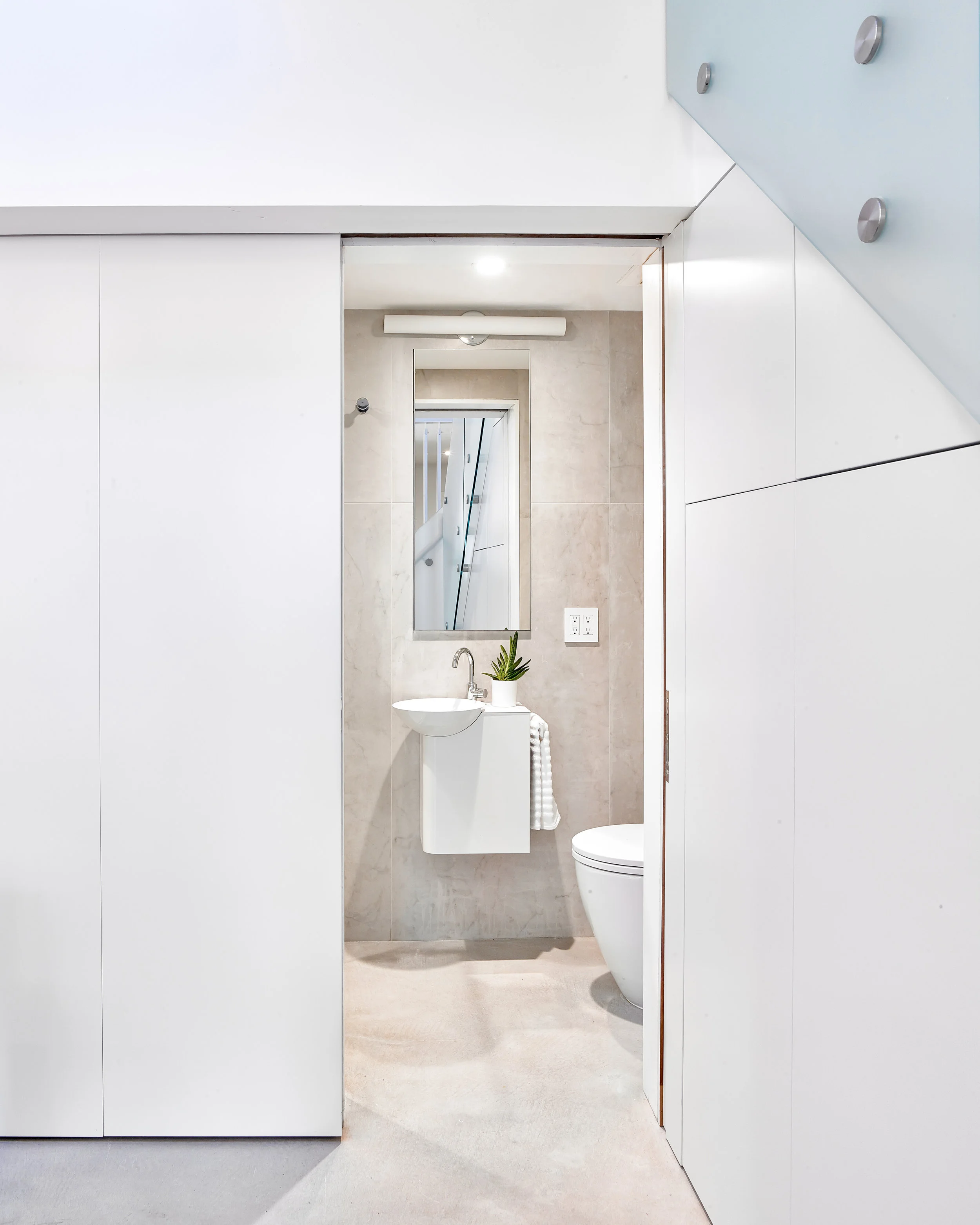 Tucked away, an efficient powder room acts as a guest bathroom and shower, but disappears completely when not in use.