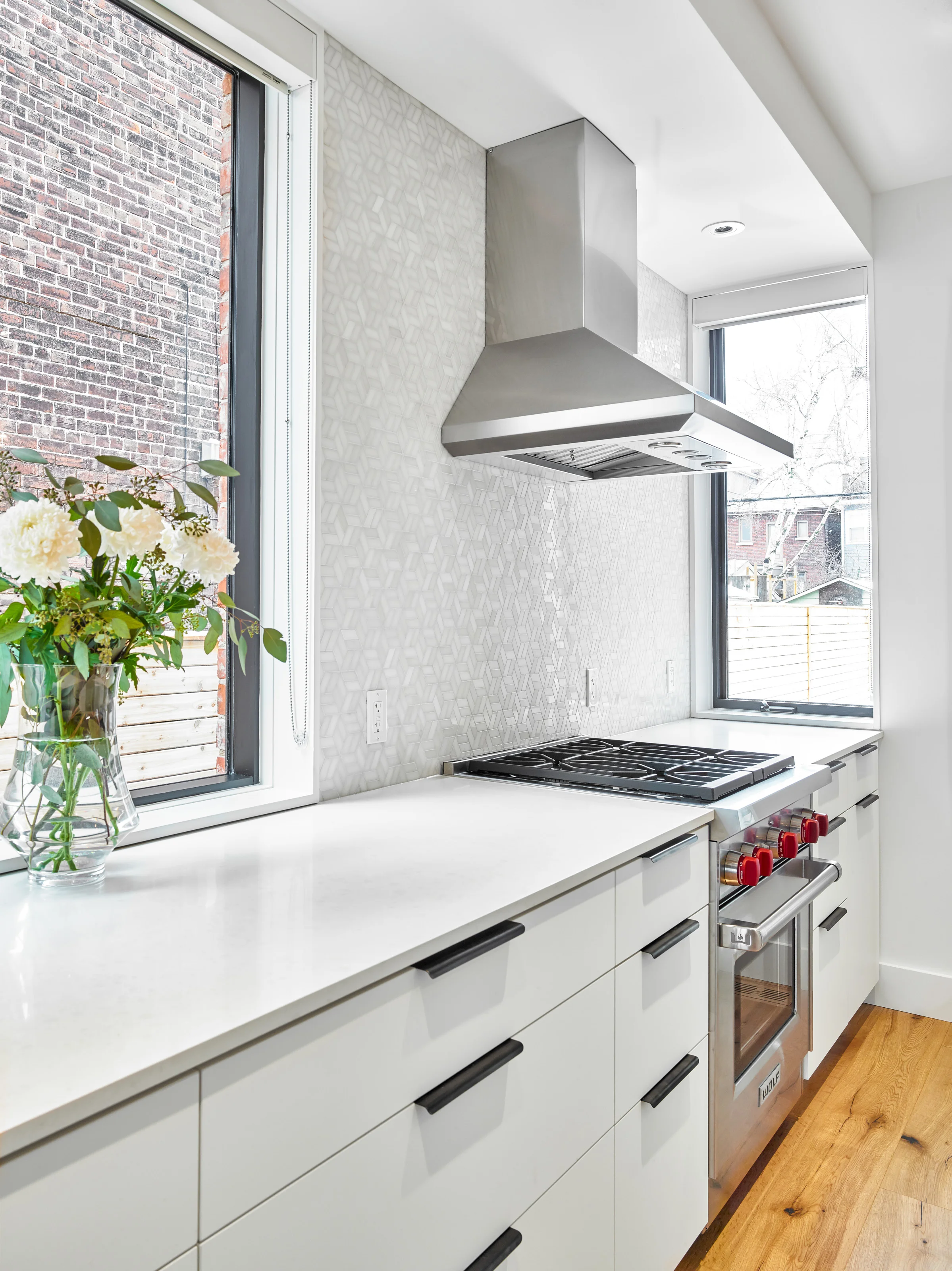 A subtle, geometric tile backsplash brings a lightness and delicacy to the kitchen. The crystalline shapes glimmer and reflect light streaming in from the generous windows.