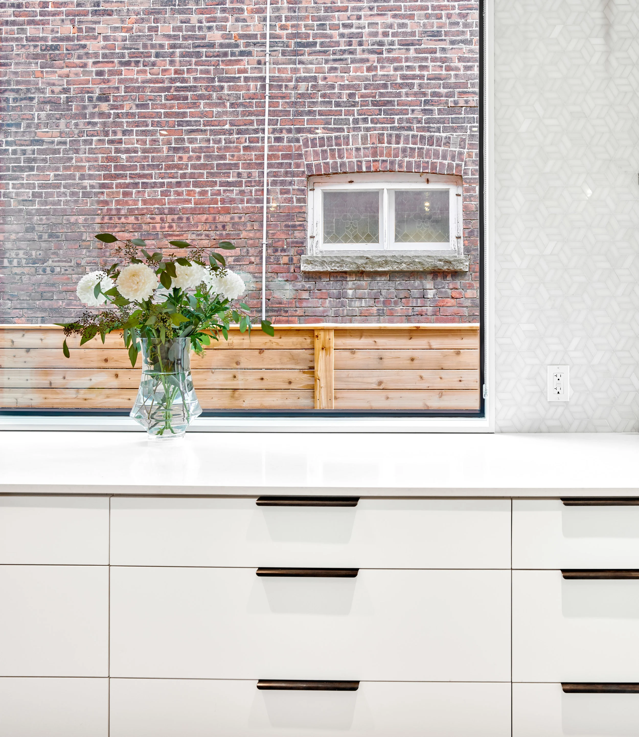 New window openings are carefully located and aligned with the countertop and bulkhead above to make the window frames disappear as much as possible and create an illusion of standing outdoors when one stands at the countertop.