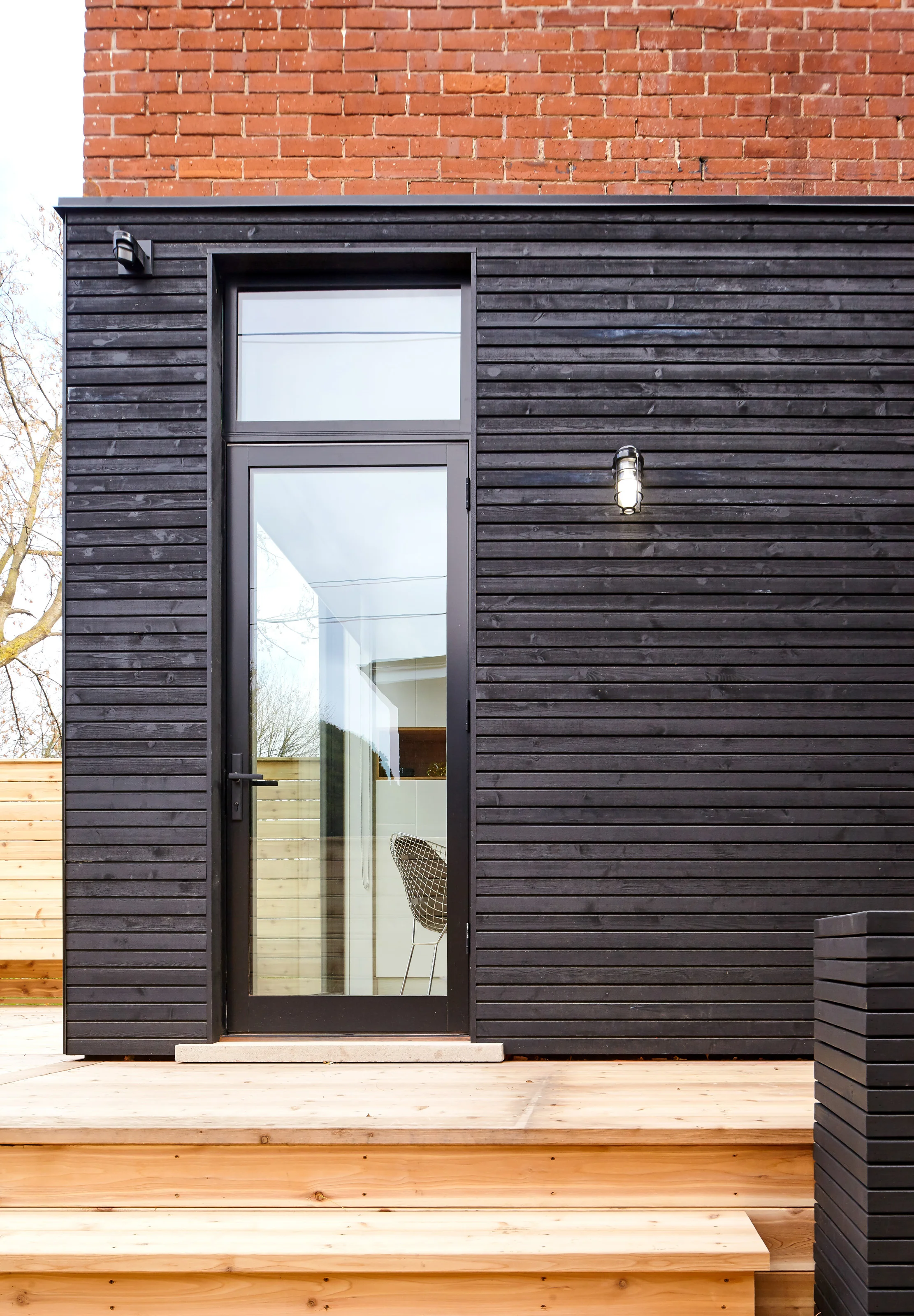 The palette of raw cedar and black-stained wood siding continues on the rear facade. Generous new windows and doors are cut into the existing home to provide generous amounts of light, and views to the yard.