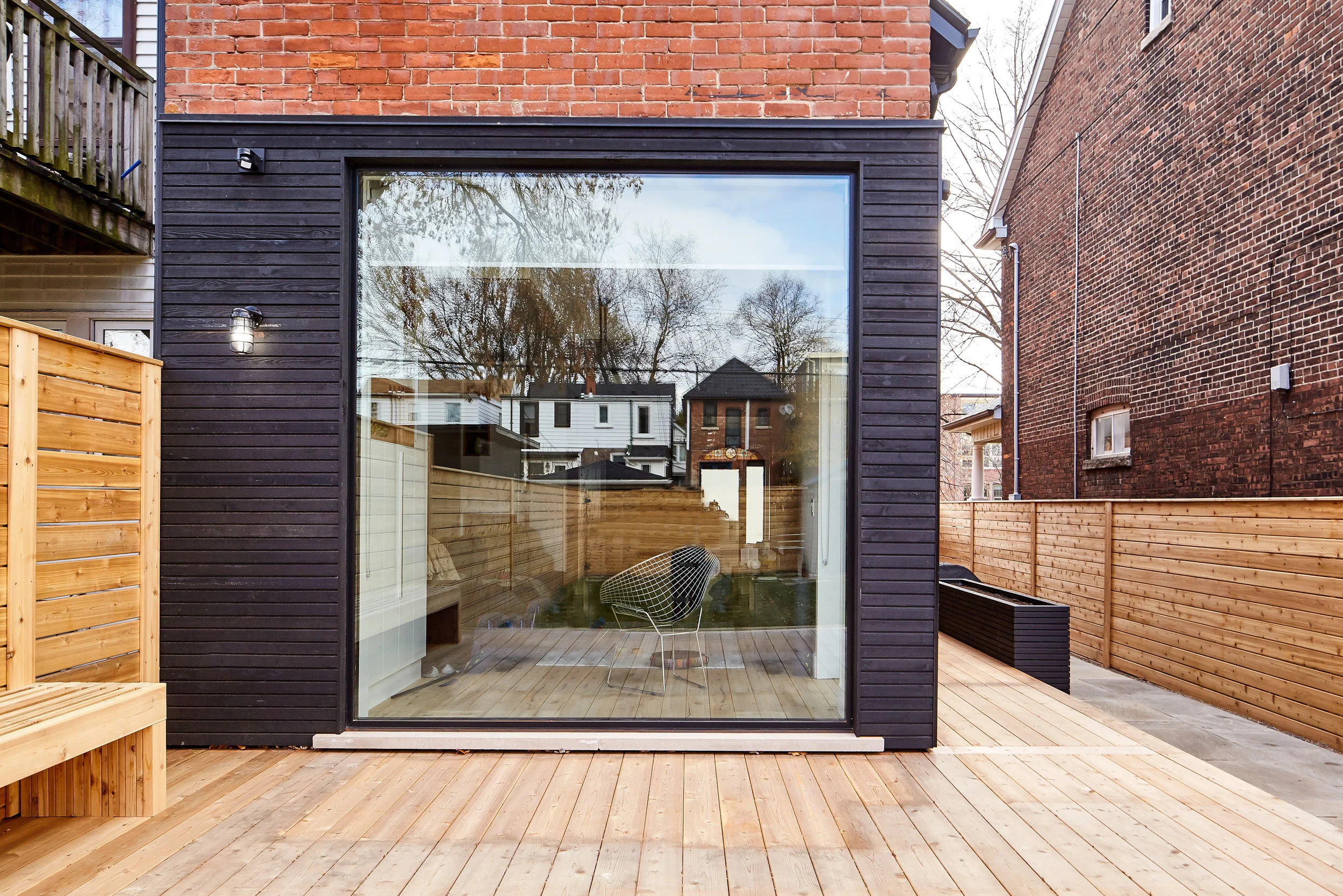 An oversized picture window at the back of the house is a bold, modern move. Instead of a sliding door, the window provides uninterrupted views and a clean, minimal appearance. Access to the yard is through a tall swing door opening to the right side.