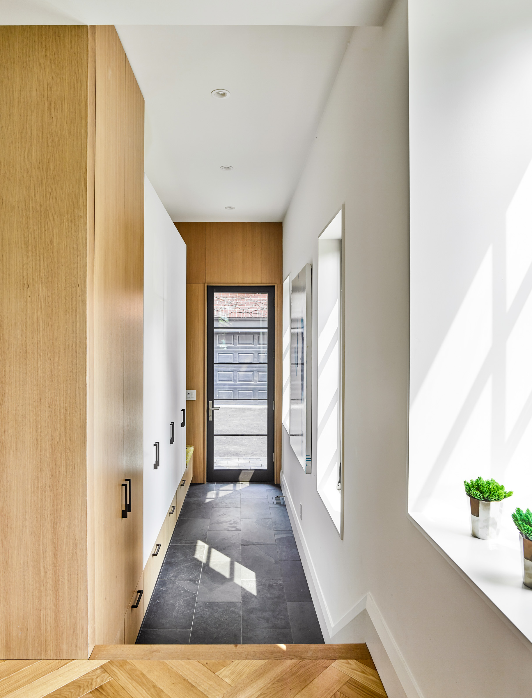 A side entrance is tucked behind the kitchen and marked by a step down to a natural slate floor, providing easy access at grade to the garage and rear yard. A bank of closets provide plenty of storage space for jackets, but are pulled down from the
