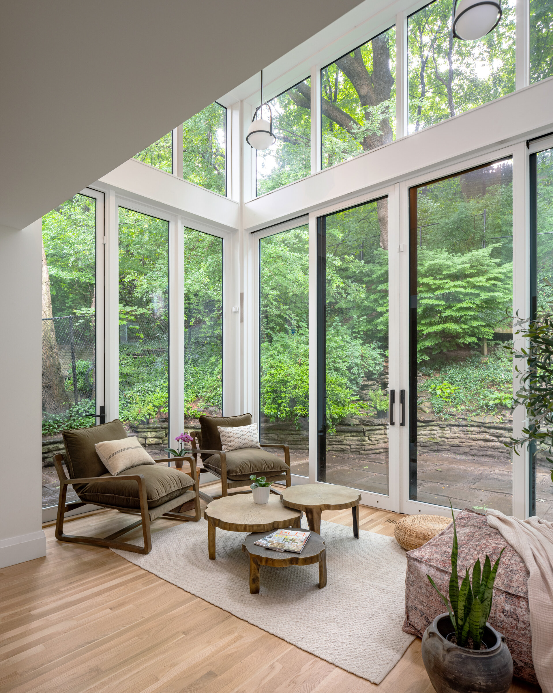 The existing two story addition was demolished and replaced with a new, single story double height space. The new glass box houses a casual seating area with lofty, uninterrupted views to the forested, ivy covered hill behind the house.