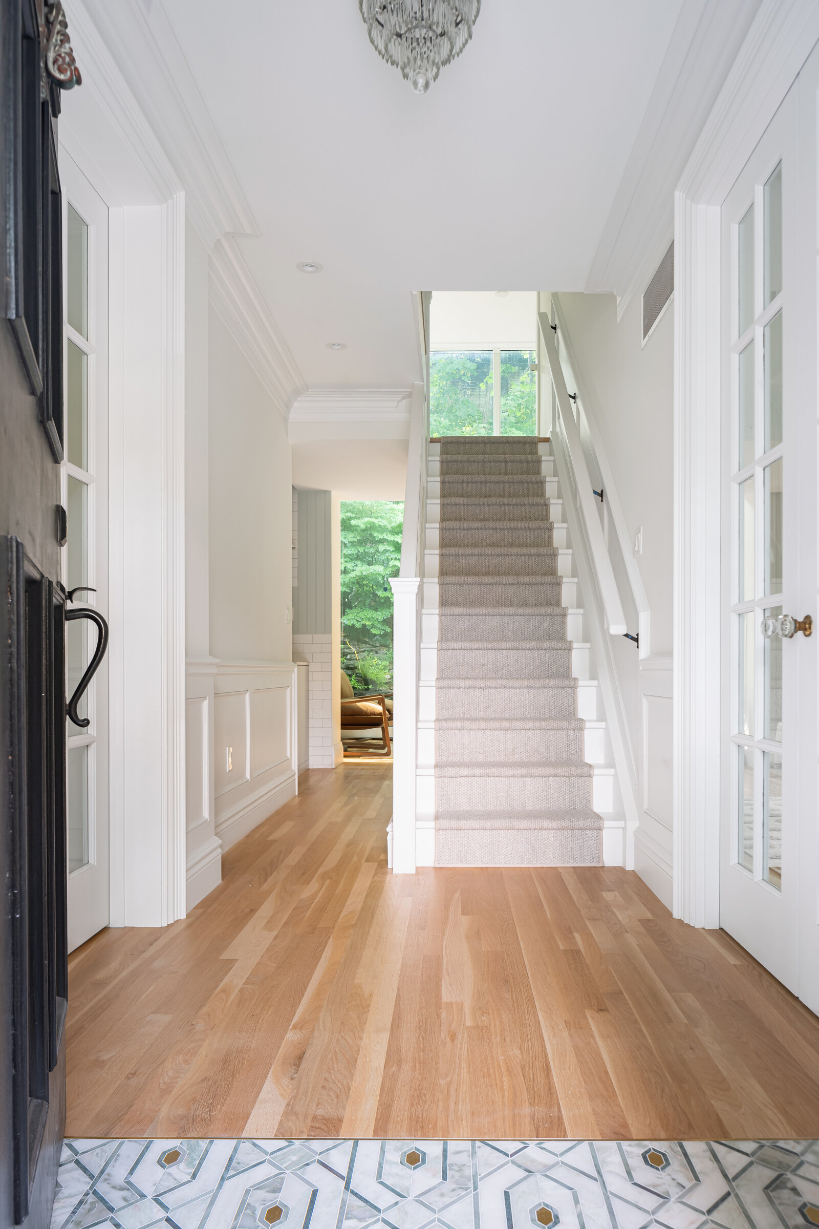 Upon entering the front door, the blend of old and new is immediately apparent. The traditional details of the more formal front of the house, such as the wainscoting and crown molding, dissolve into a modern glassy addition that affords a view str