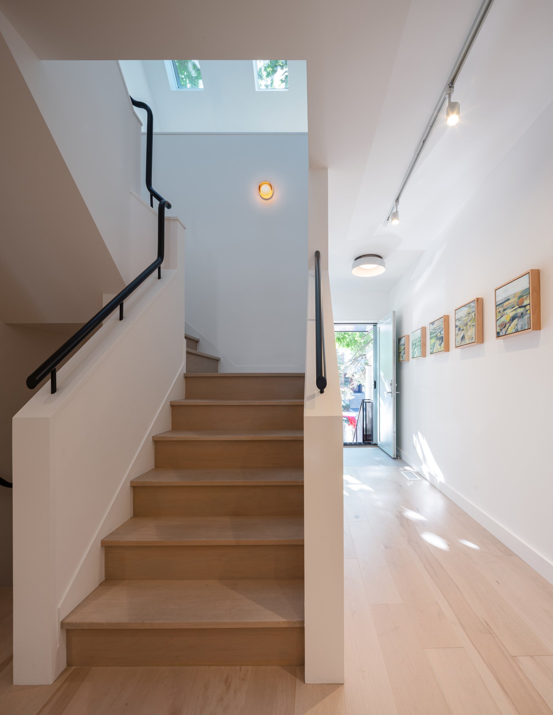 Locating the staircase towards the centre of the floorplan allows it to act as a light well, bringing sunlight down to the ground floor from the skylights above. Beside the stair, a long gallery wall provides display space for the client’s extensive