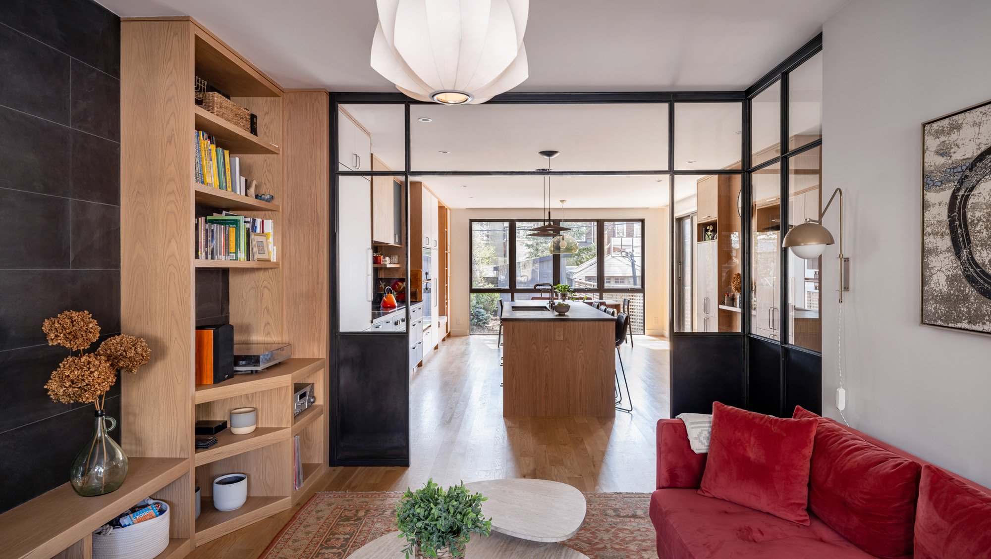 The kitchen millwork band extends into the living room and becomes a bookcase with space for the record player and some albums. The slate backsplash in the kitchen extends into the living room as well, becoming a dramatic feature wall that adds dept