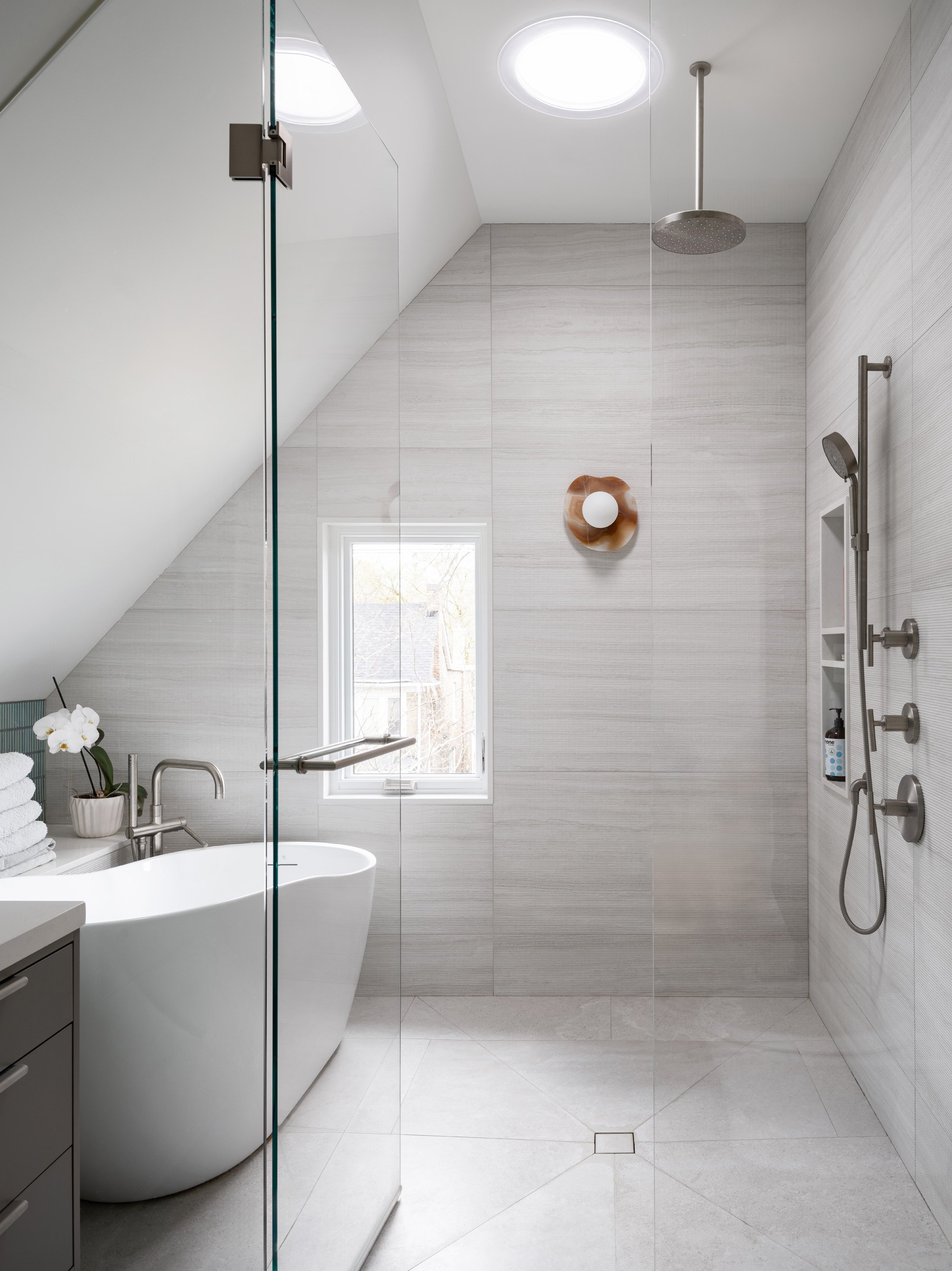 The ensuite bathroom has a large walk-in shower and tub with a view. A mixture of large format tiles with subtle texture and mint ceramic tiles creates a calming palette, without sacrificing texture or colour.