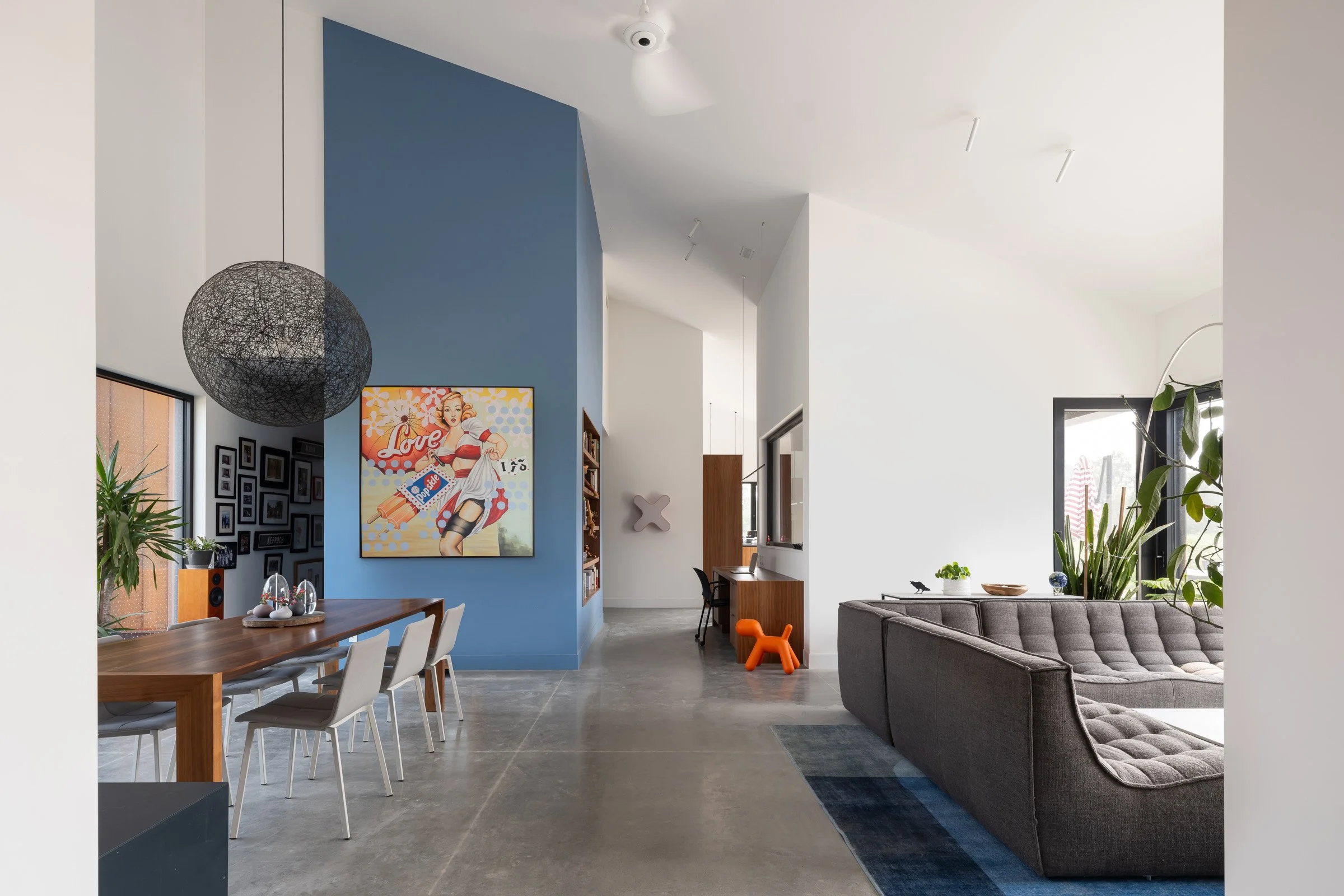  The large, vaulted peak of the main living space is expressed on the interior. The soaring ceiling creates a feeling of spaciousness. A central volume which conceals the laundry room is painted blue and provides a striking and colourful focal point 
