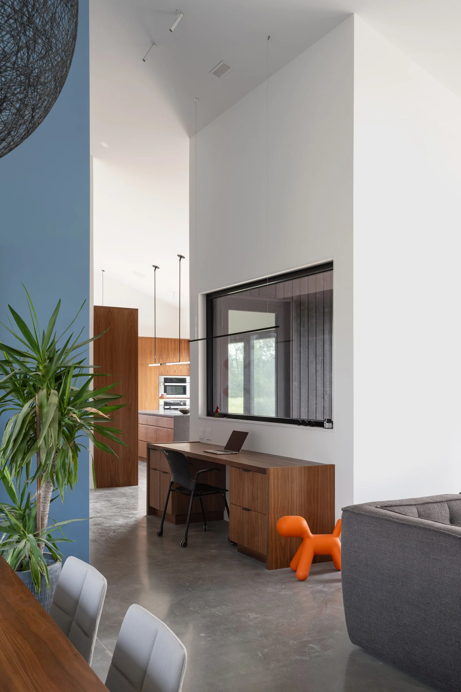  A small workspace is tucked between the kitchen and living room, with a view out to the large deck, and meadow beyond. 