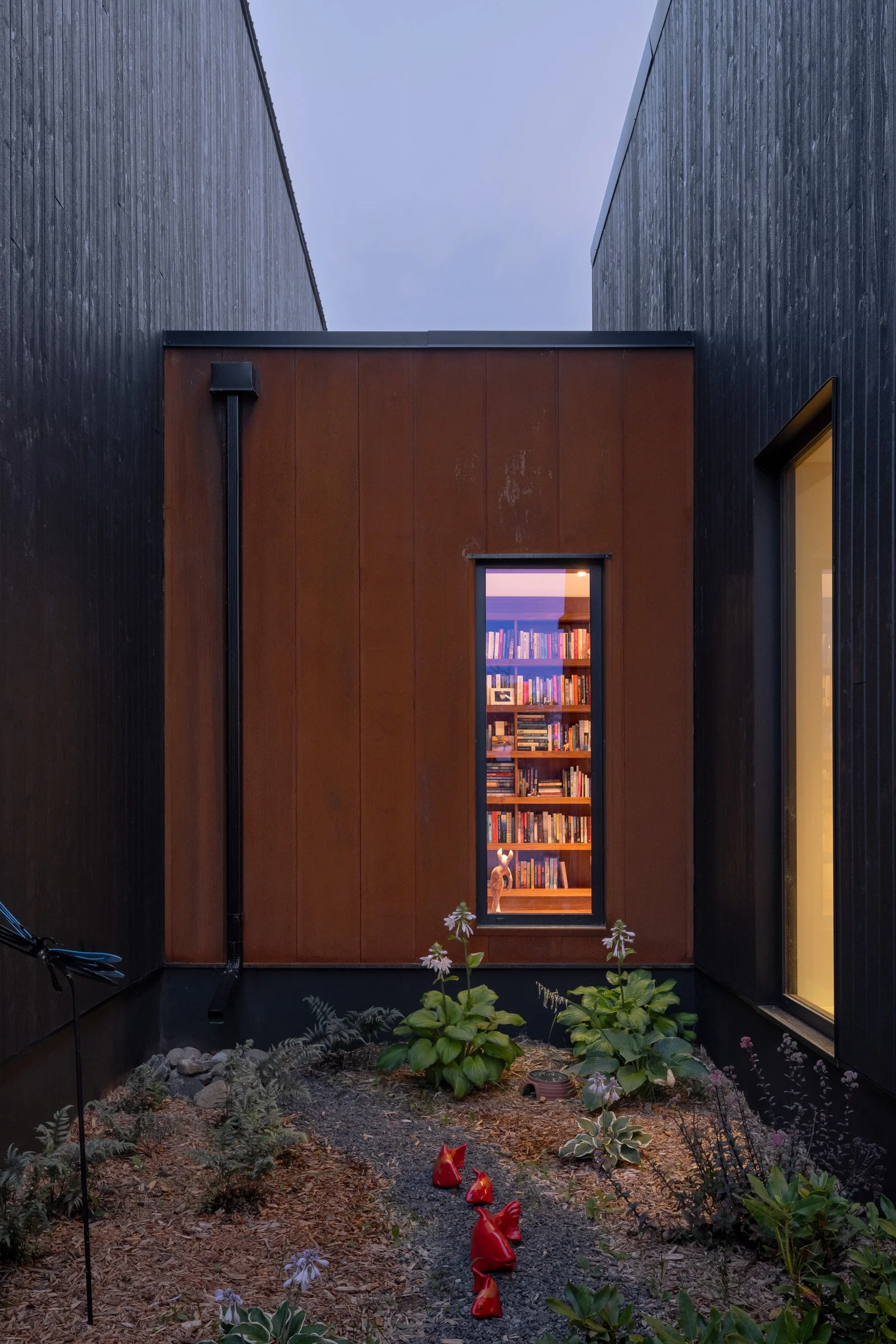  At night, the illuminated hallway glows within. The garden flows right up to the house in the spaces created between the volumes. 
