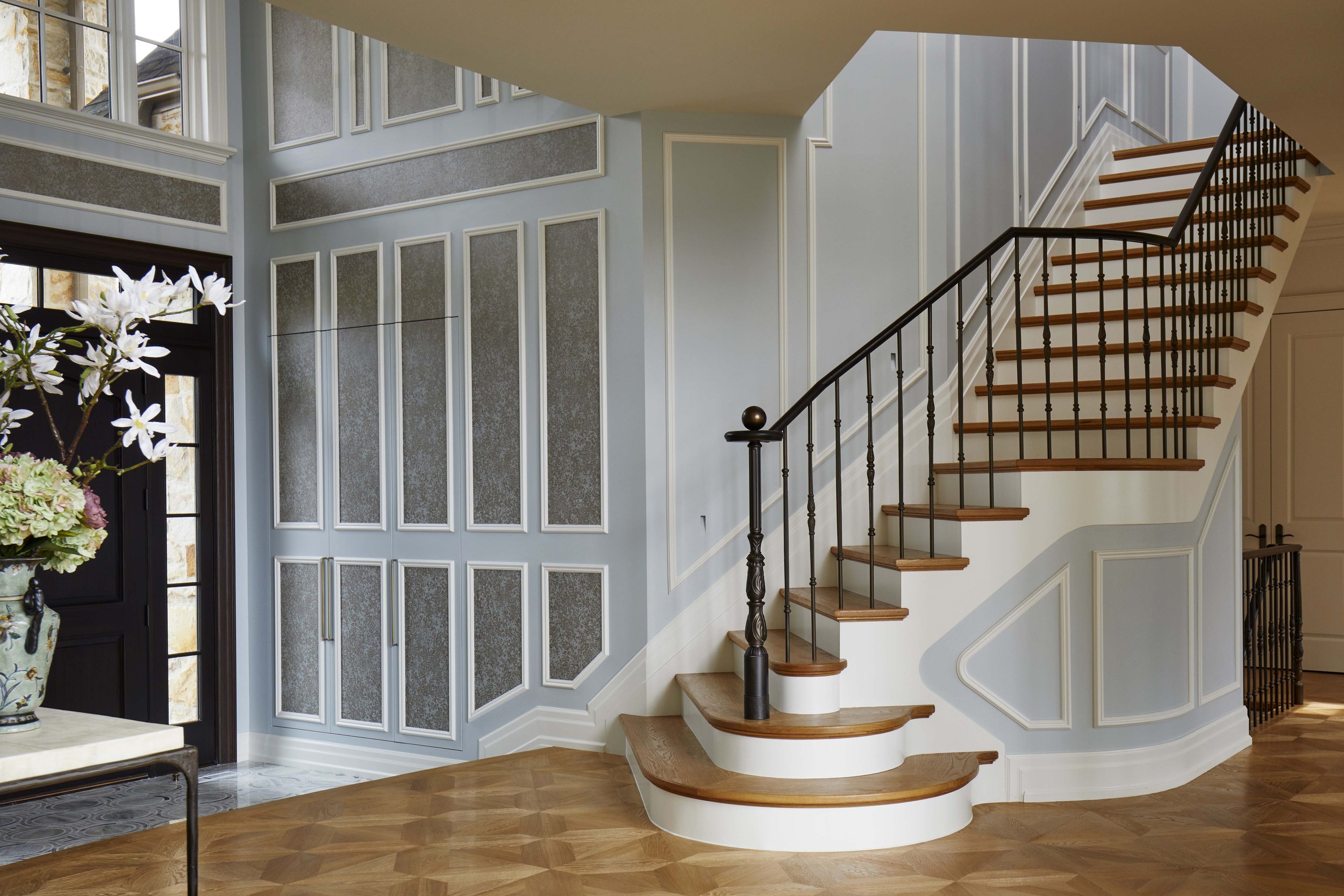  A new staircase and custom bronze railing spill out into the centre of the ground floor. New closets are concealed in the wallpaper and paneled walls in the foyer behind to address the lack of storage in the entry. 