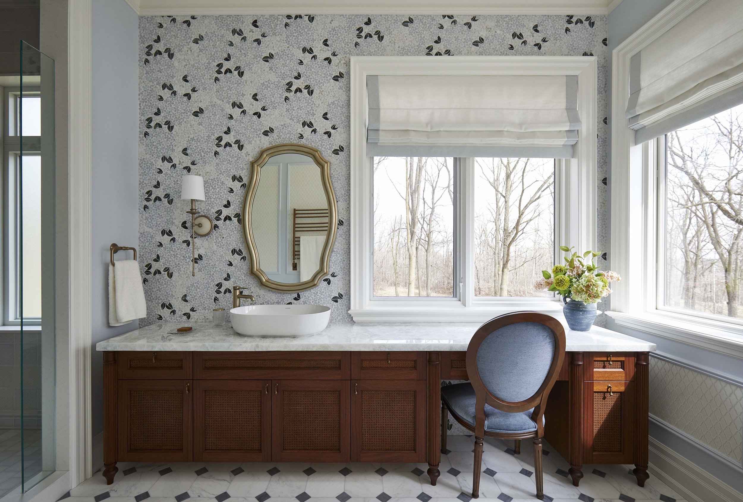  The primary ensuite is filled with pale, watery blues and softly glittering marble. The centrepiece of the room is a custom mahogany vanity designed to feel like an antique furniture piece. A custom marble mosaic covers the wall, acting like a luxur