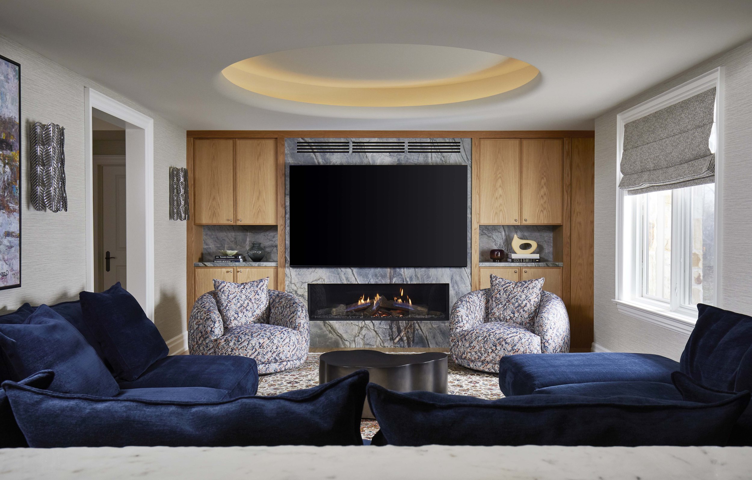  This room is the main TV watching space in the house and is designed for family movie nights. A large U-shaped Montauk sofa can comfortably seat the whole family and is upholstered in a rich deep blue fabric. A circular recessed cove light on the ce
