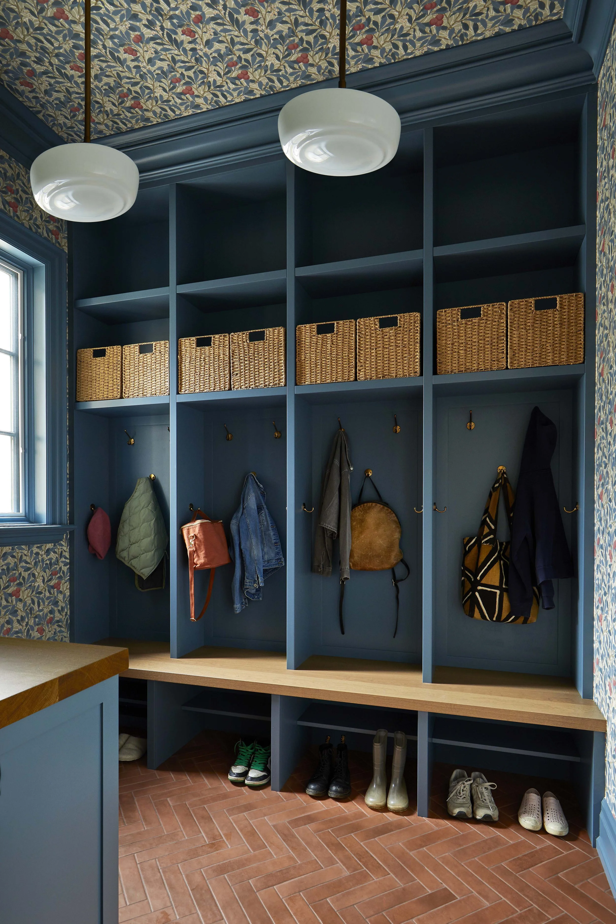 A new boot room located off the side door is designed to contain all the daily mess of coming and going. Each child has their own cubby and space on a shared bench with lots of storage for shoes, coats, and accessories. William Morris wallpaper add 