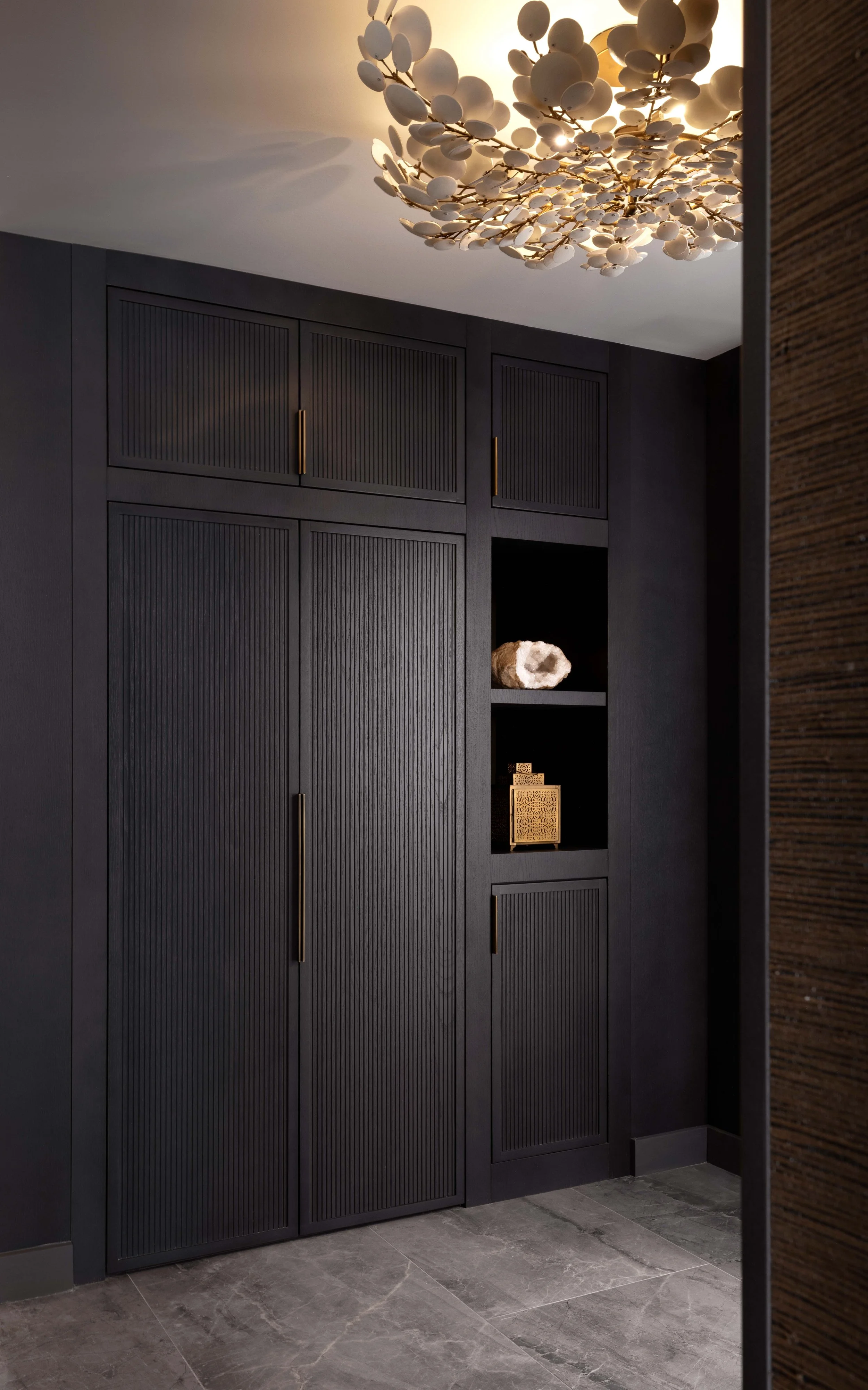  Upon entering, you are immersed in a dark, textural entry that blends grey stained oak and bronze. Generous closet space is offered on both sides of the foyer, giving ample storage. 