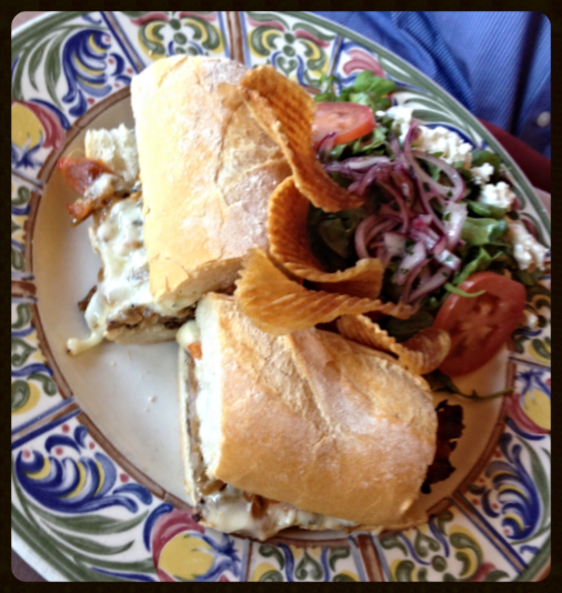 The New York: filet mignon, caramelized onions and cheese on baguette with additional arugula salad topped with goat cheese